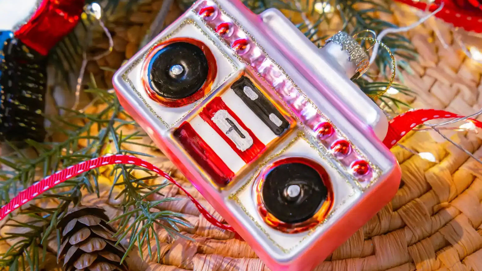 Chive glass boombox ornament in pink hanging on a holiday tree.