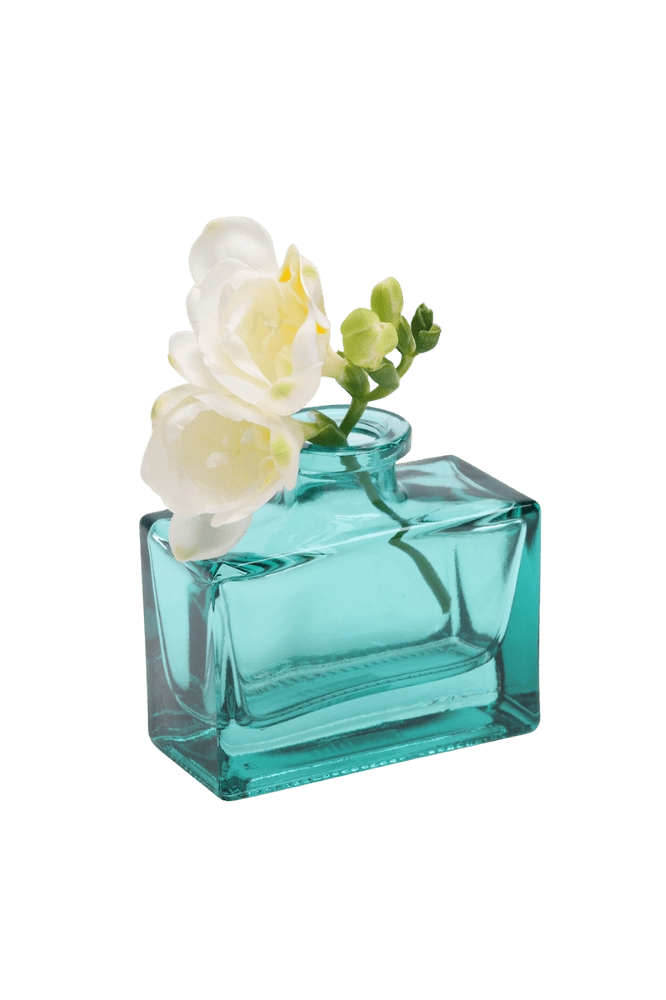 Chive Loft glass bud vase in Teal cradles white freesia at an angle, showing the jar's full shape.