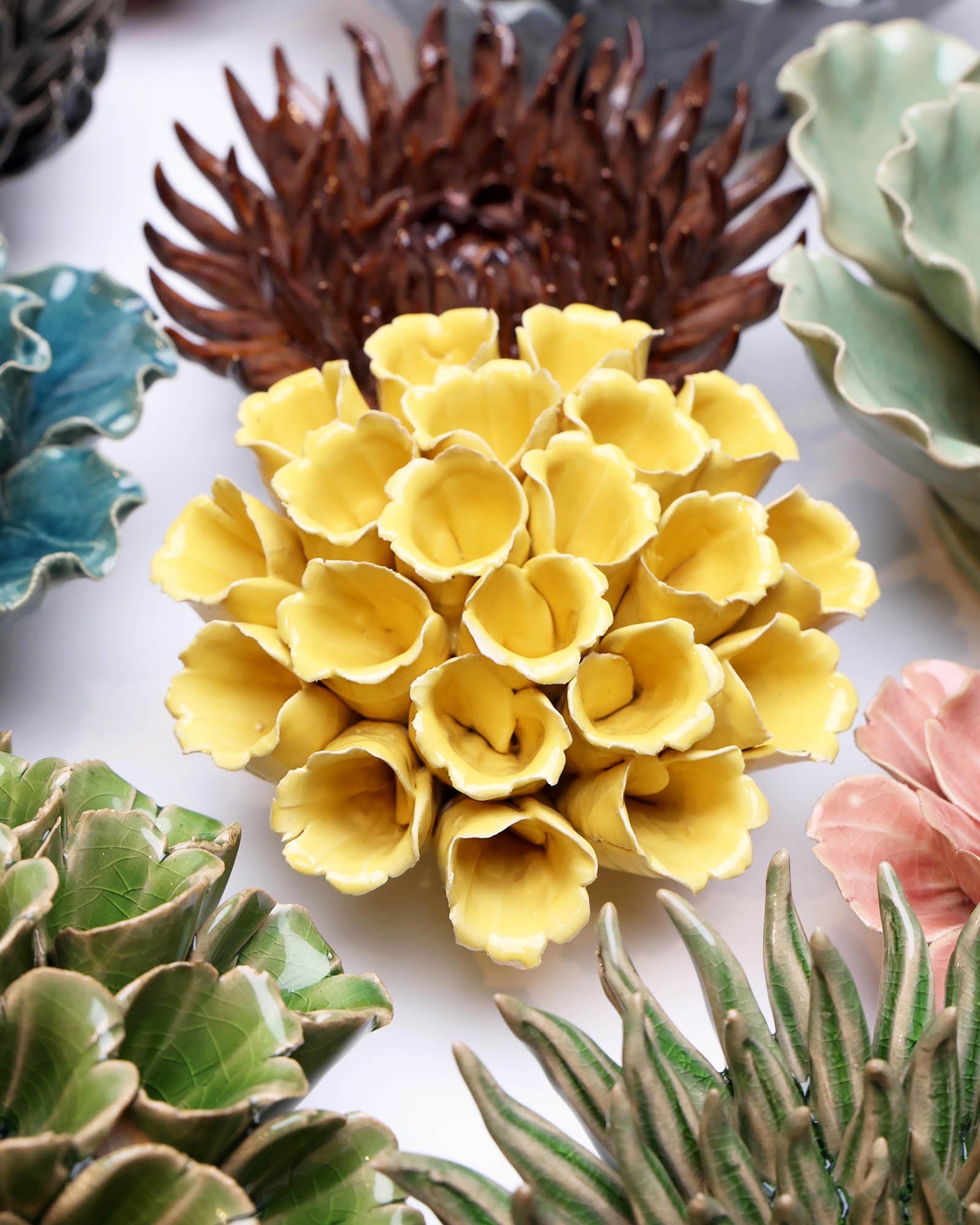 Polyp Yellow Medium ceramic wall flower styled on a white table with other flowers — Chive Studio