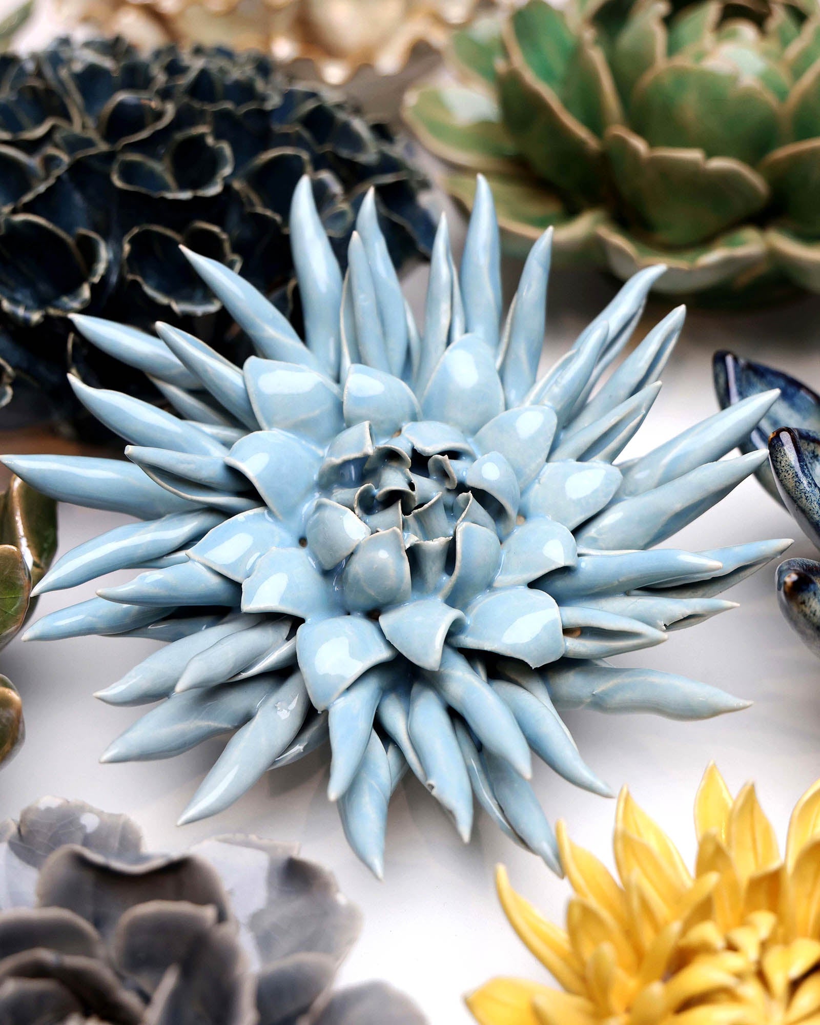 Flower Blue 6 ceramic wall flower styled on a white table with other flowers — Chive Studio