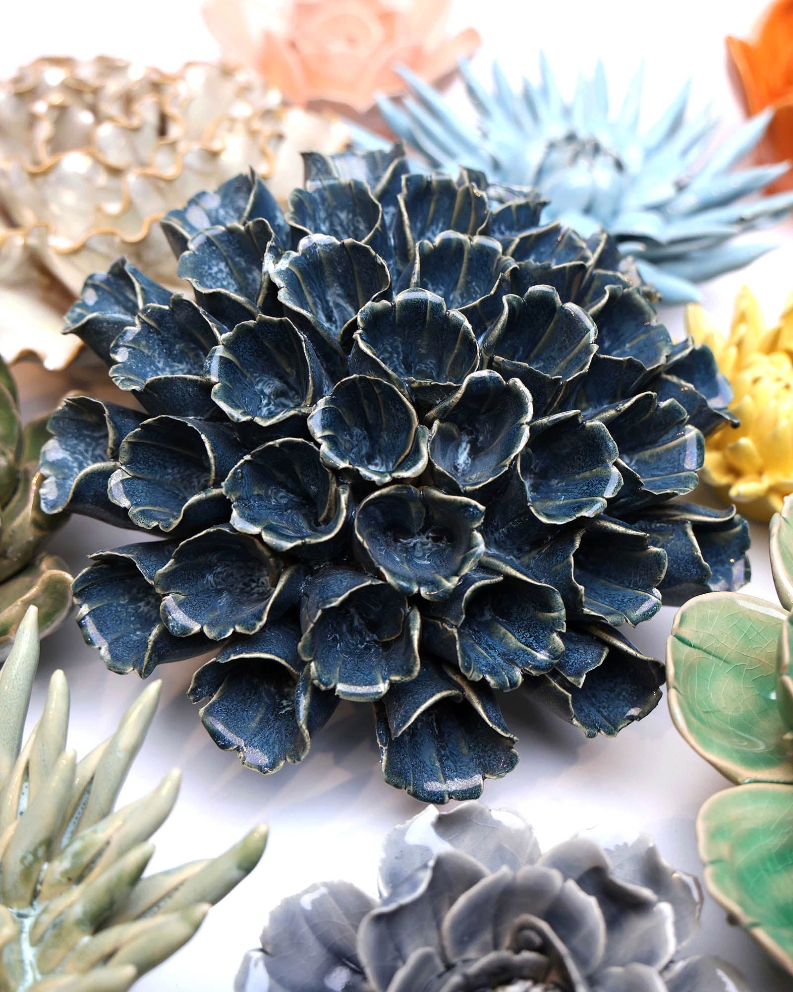 Polyp Blue 6 ceramic wall flower styled on a white table with other flowers — Chive Studio