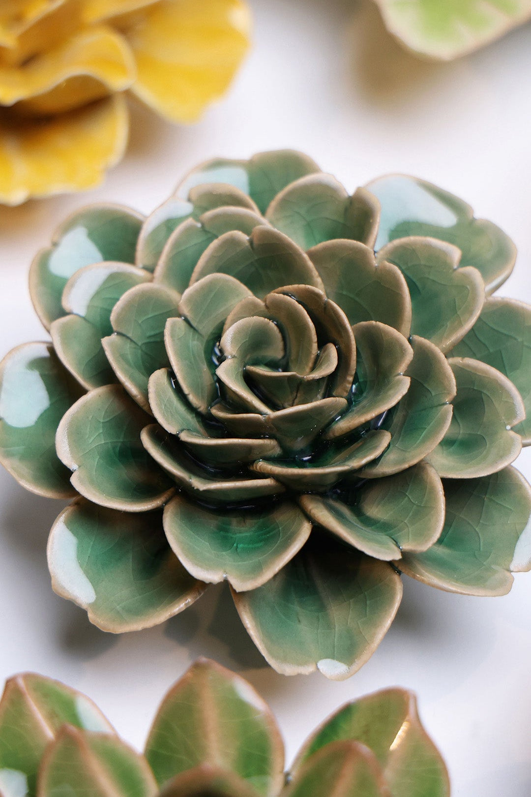 Jungle Green Rose ceramic wall flower styled on a white table with other flowers — Chive Studio