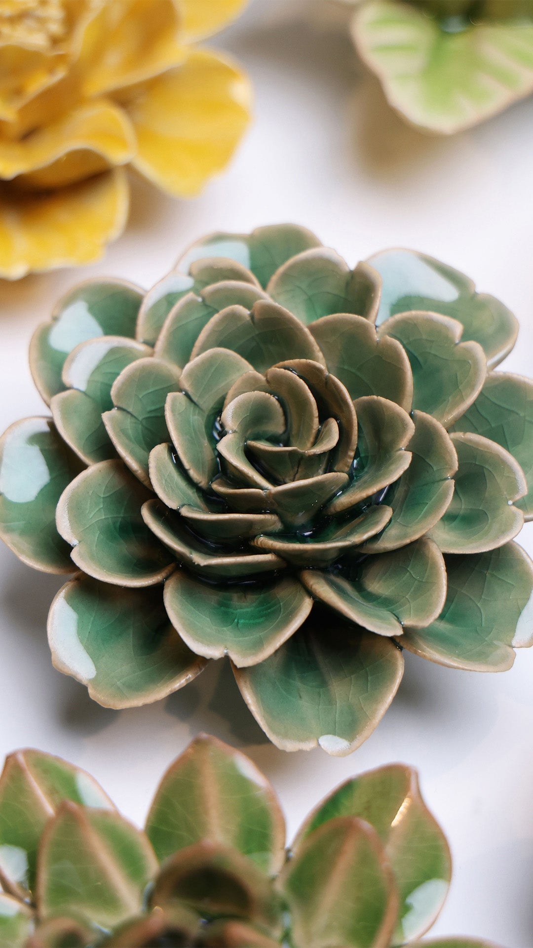 Jungle Green Rose ceramic wall flower styled on a white table with other flowers — Chive Studio