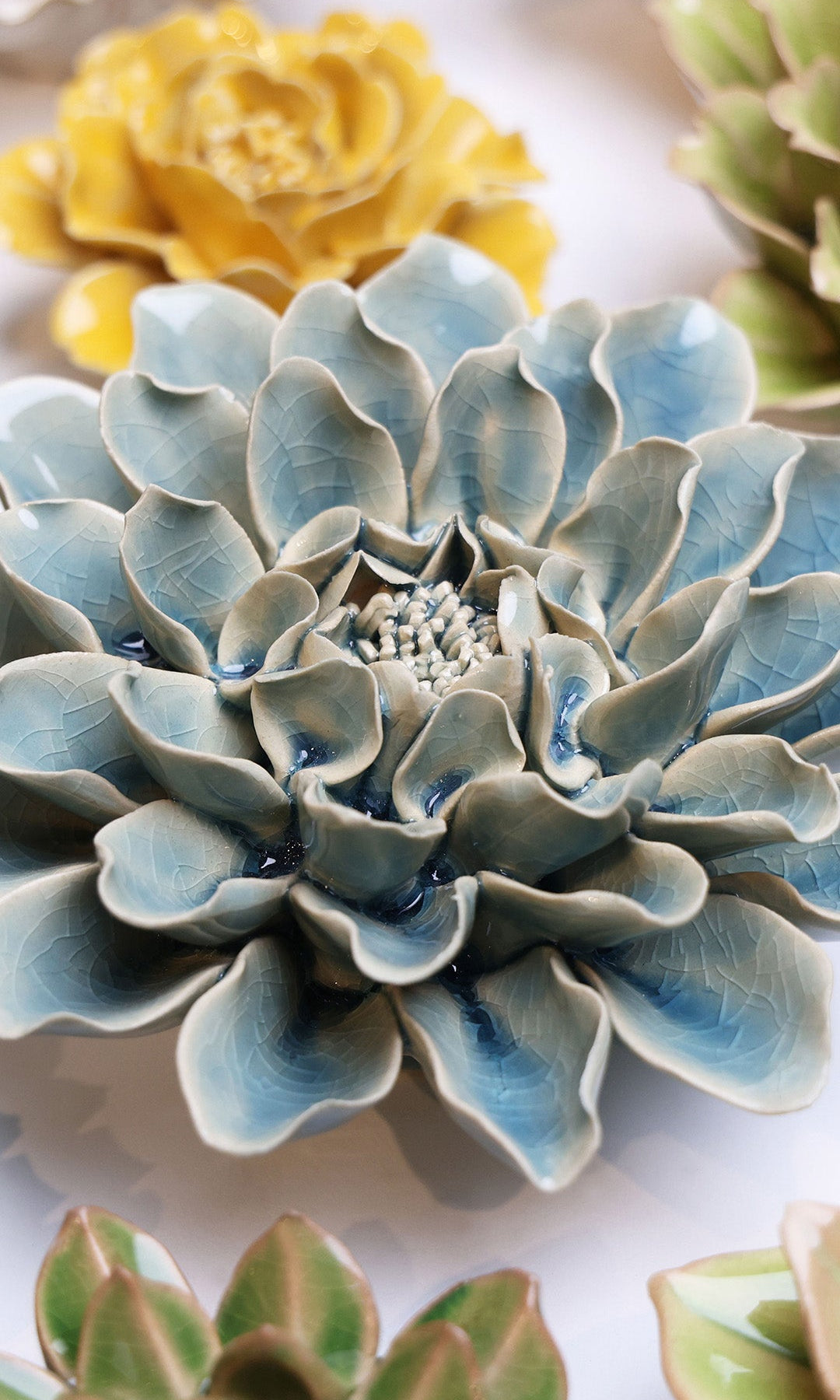 Powder Blue Aphrodite Dahlia ceramic wall flower styled on a white table with other flowers — Chive Studio