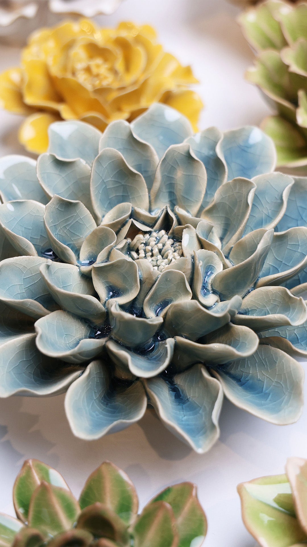 Powder Blue Aphrodite Dahlia ceramic wall flower styled on a white table with other flowers — Chive Studio