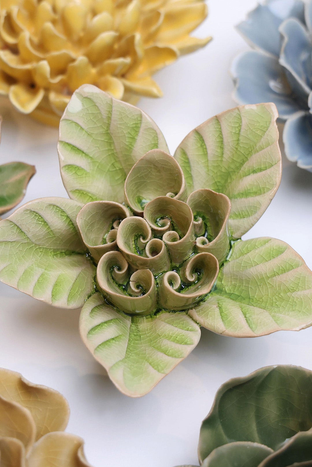 Peridot Lotus ceramic wall flower styled on a white table with other flowers — Chive Studio