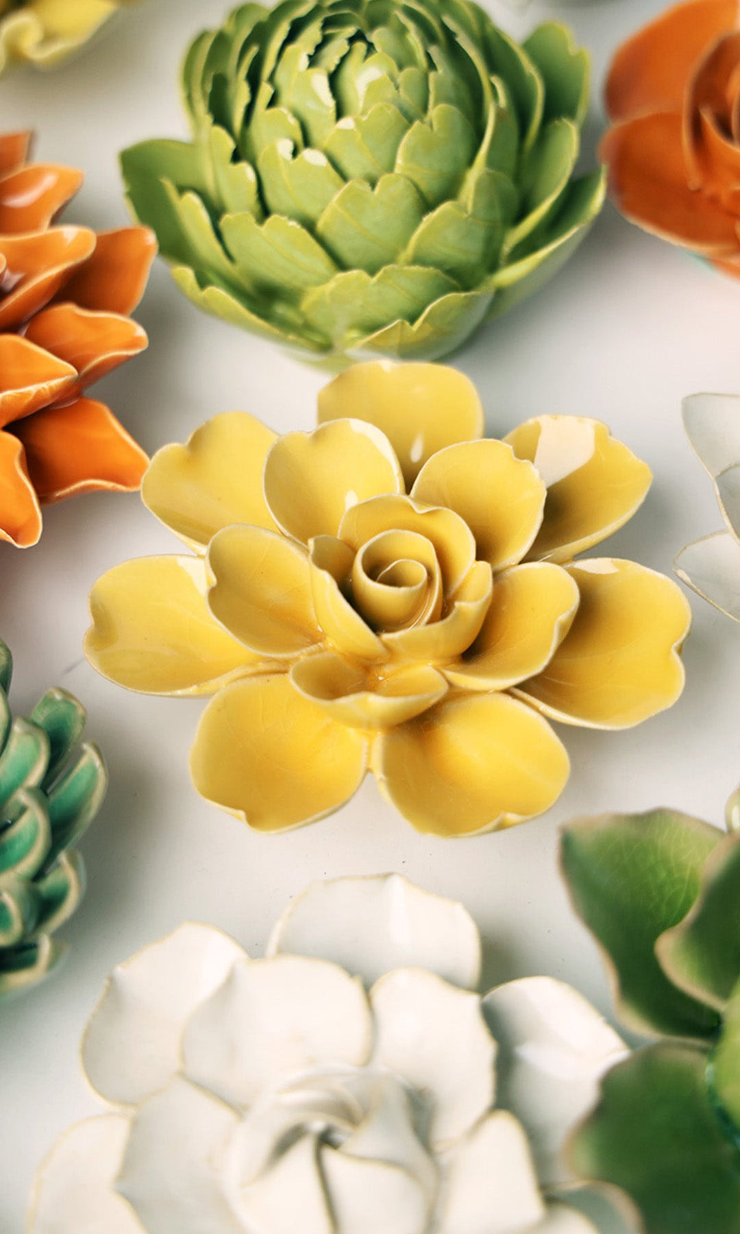 Burnt Yellow Gardenia ceramic wall flower styled on a white table with other flowers — Chive Studio
