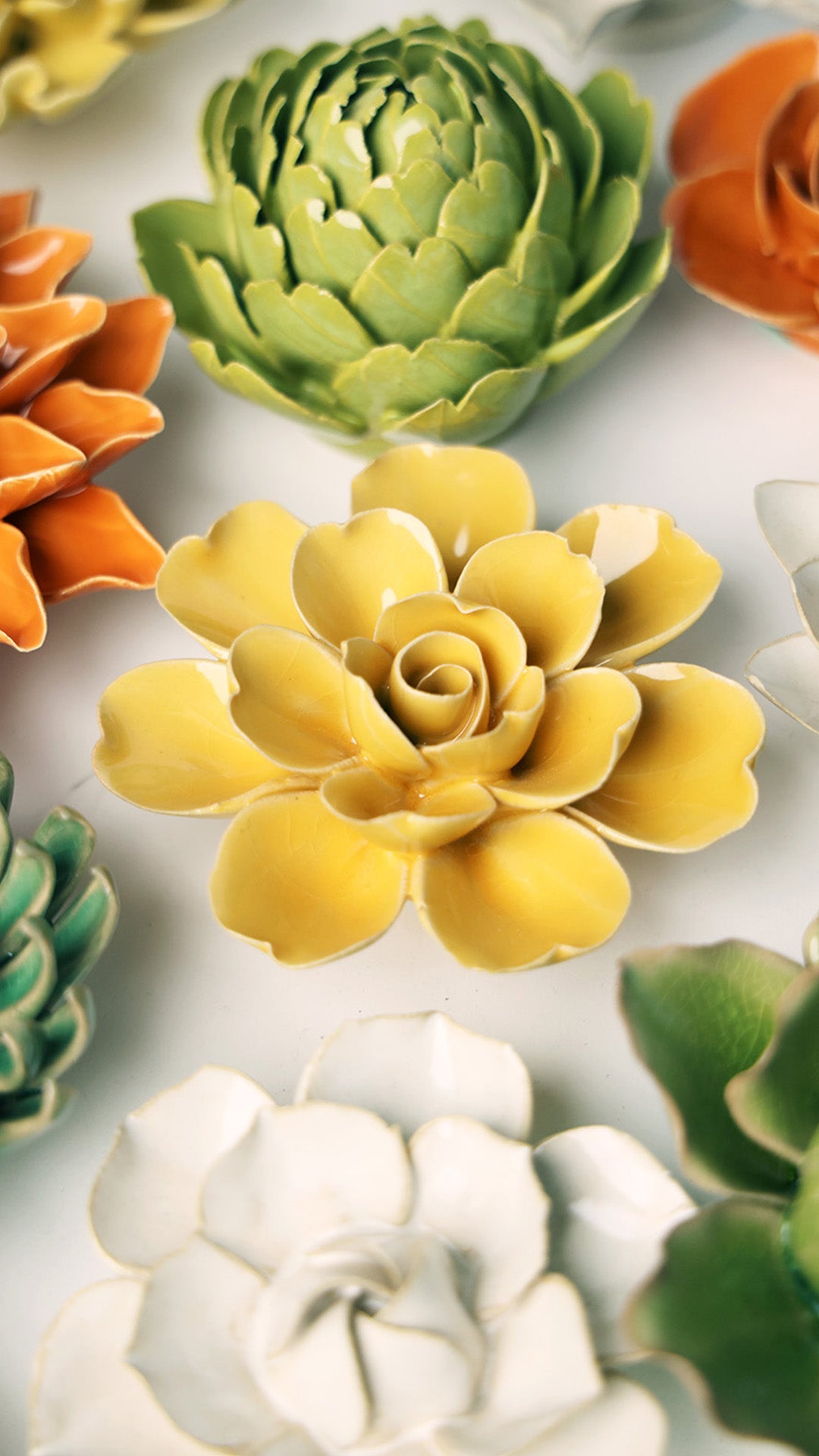 Burnt Yellow Gardenia ceramic wall flower styled on a white table with other flowers — Chive Studio