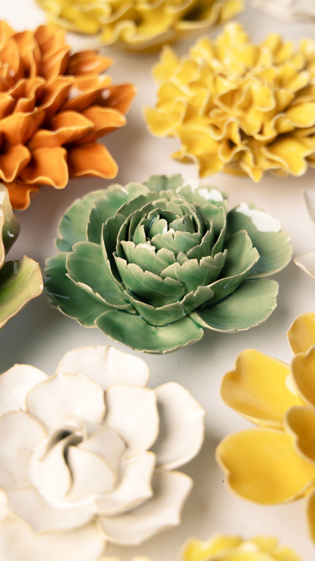 Green Rose ceramic wall flower styled on a white table with other flowers — Chive Studio