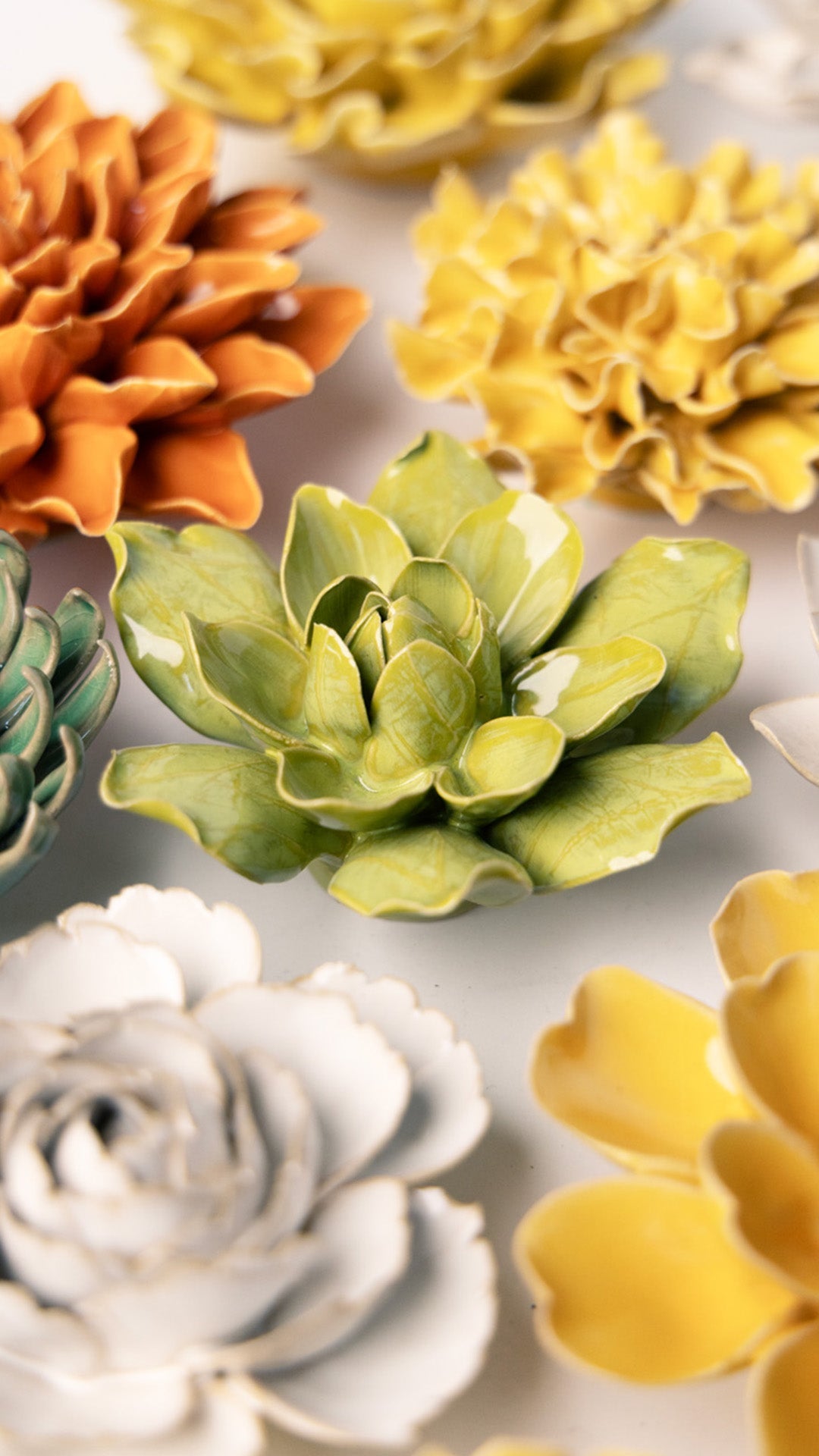 Chartreuse Columbine ceramic wall flower styled on a white table with other flowers — Chive Studio