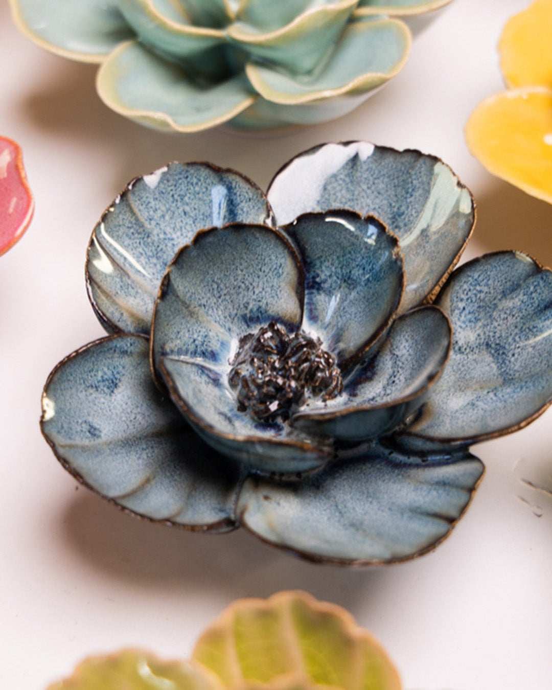 Navy Blue Poppy ceramic wall flower styled on a white table with other flowers — Chive Studio