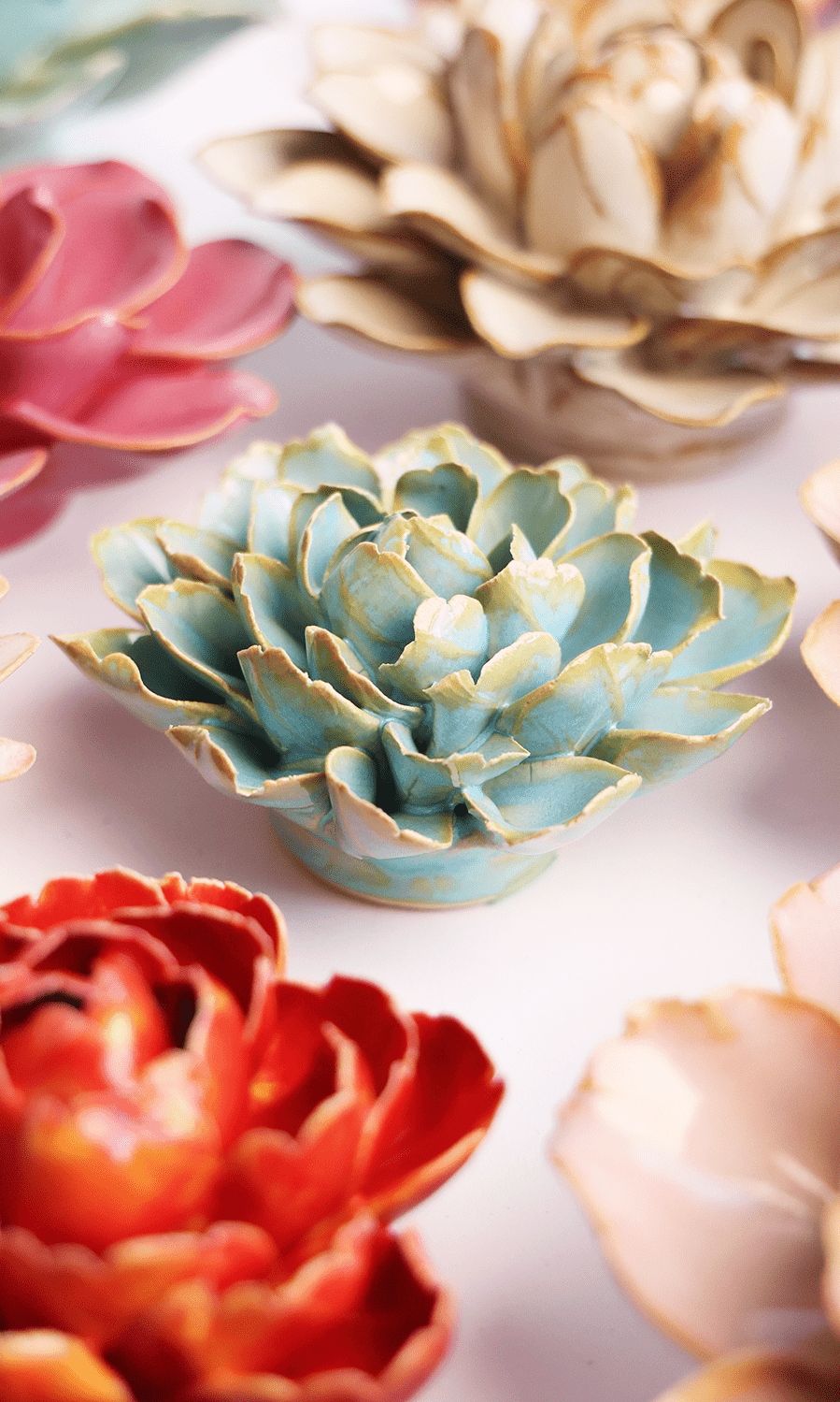 Robin's Egg Blue Marigold ceramic wall flower styled on a white table with other flowers — Chive Studio
