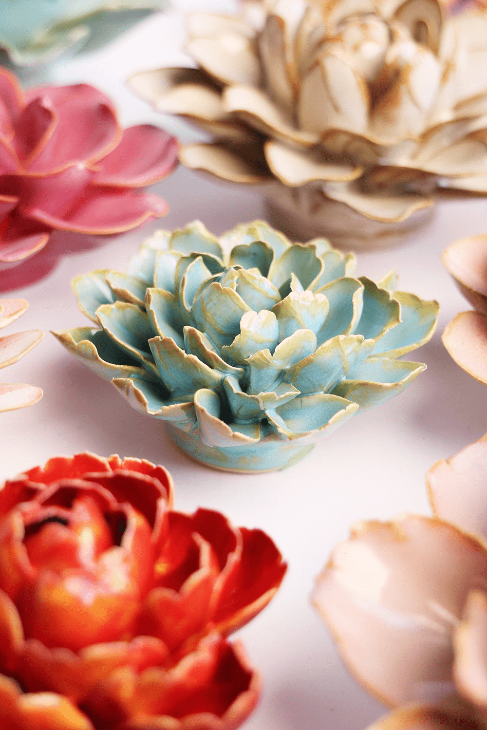 Robin's Egg Blue Marigold ceramic wall flower styled on a white table with other flowers — Chive Studio