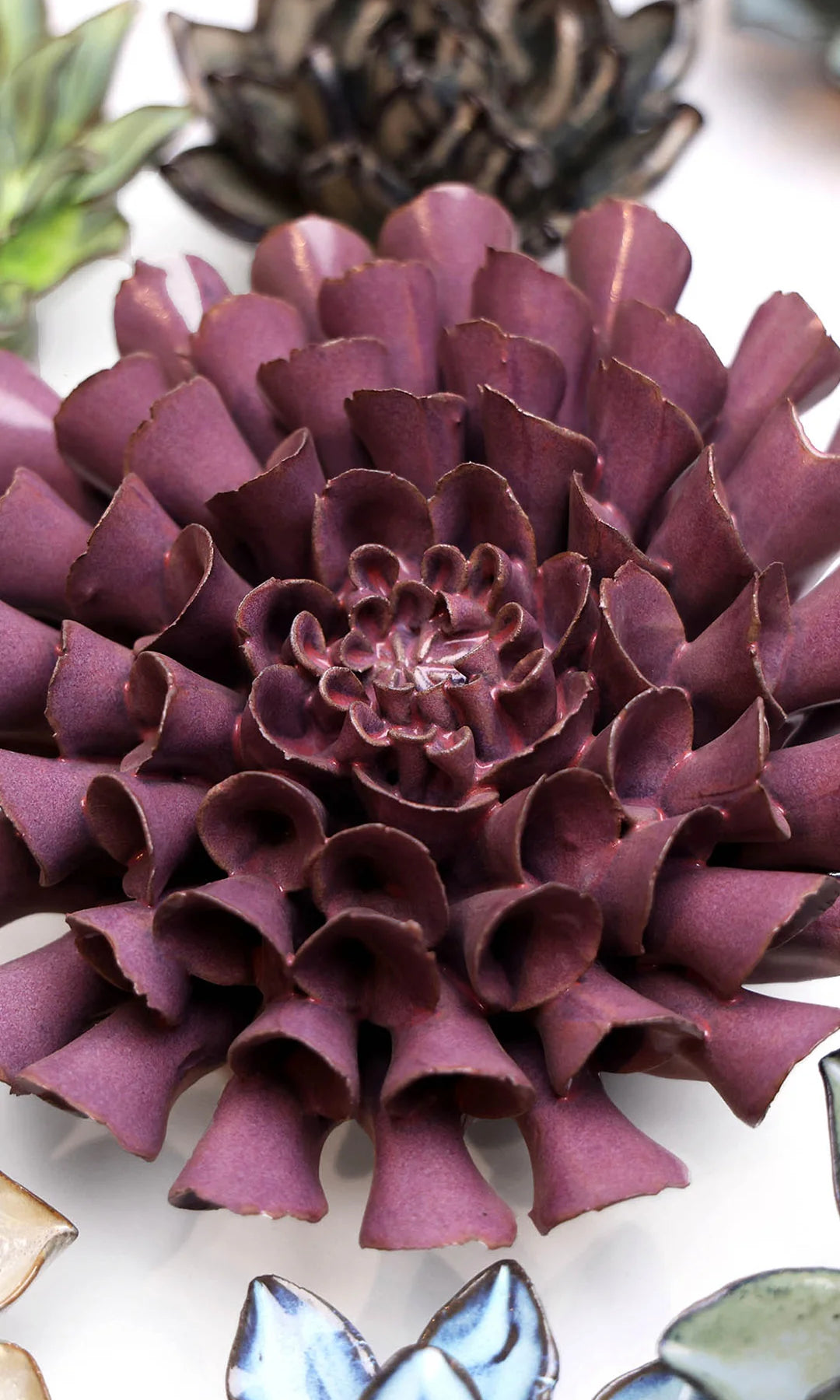 Violet Blue Dahlia ceramic wall flower styled on a white table with other flowers — Chive Studio