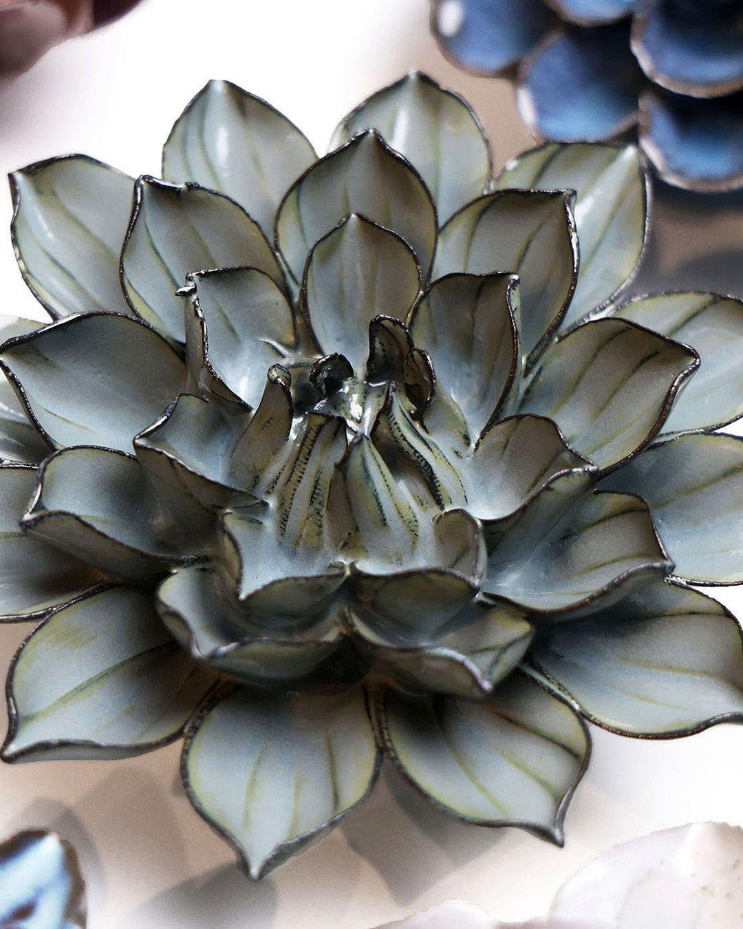 Green Monch Aster ceramic wall flower styled on a white table with other flowers — Chive Studio
