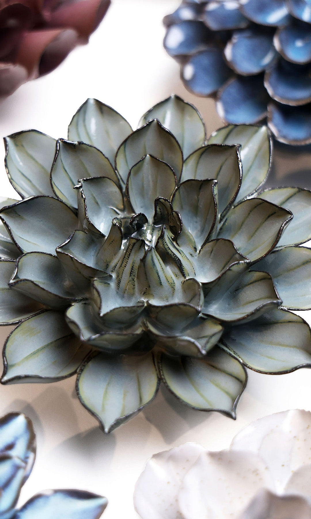 Green Monch Aster ceramic wall flower styled on a white table with other flowers — Chive Studio