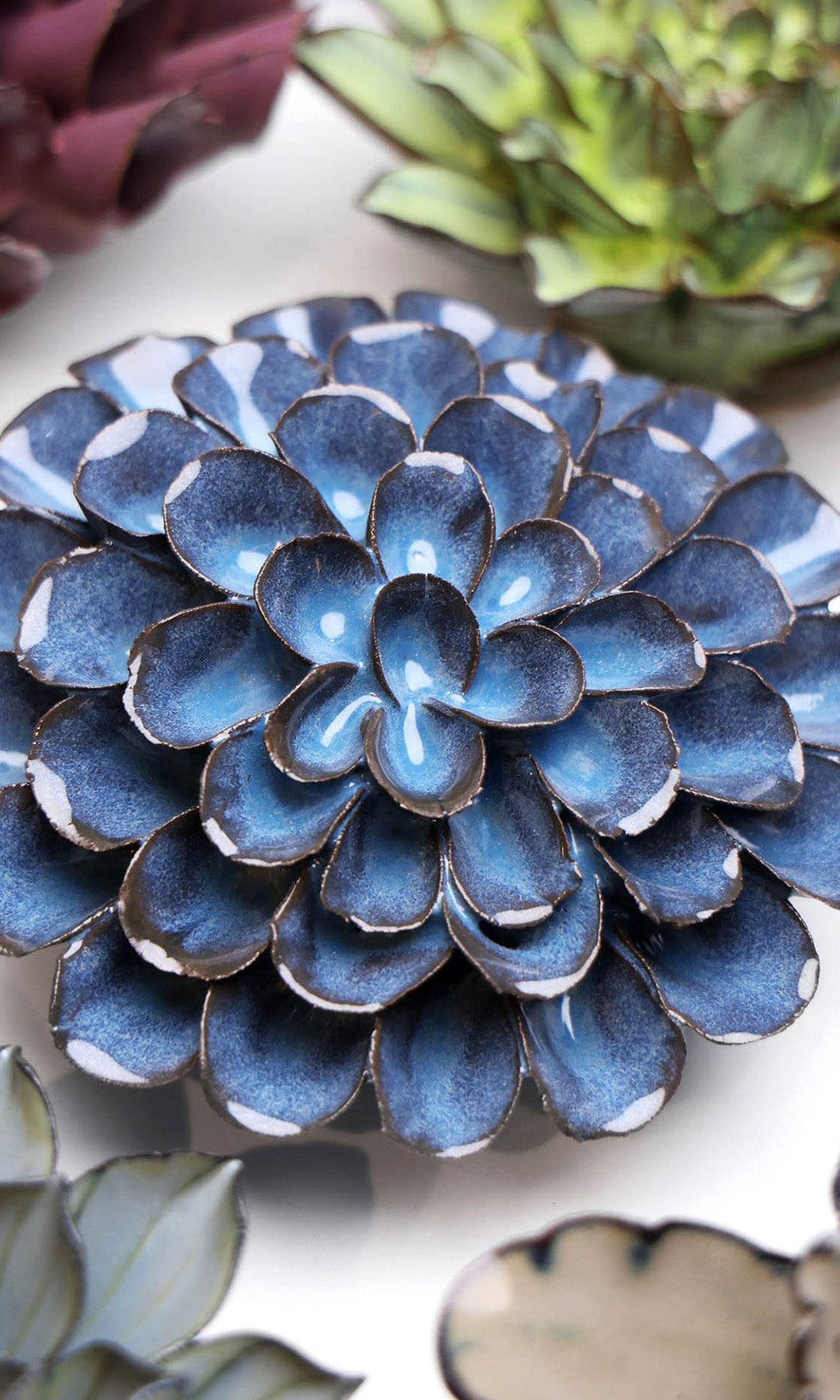 Blue Dahlia ceramic wall flower styled on a white table with other flowers — Chive Studio