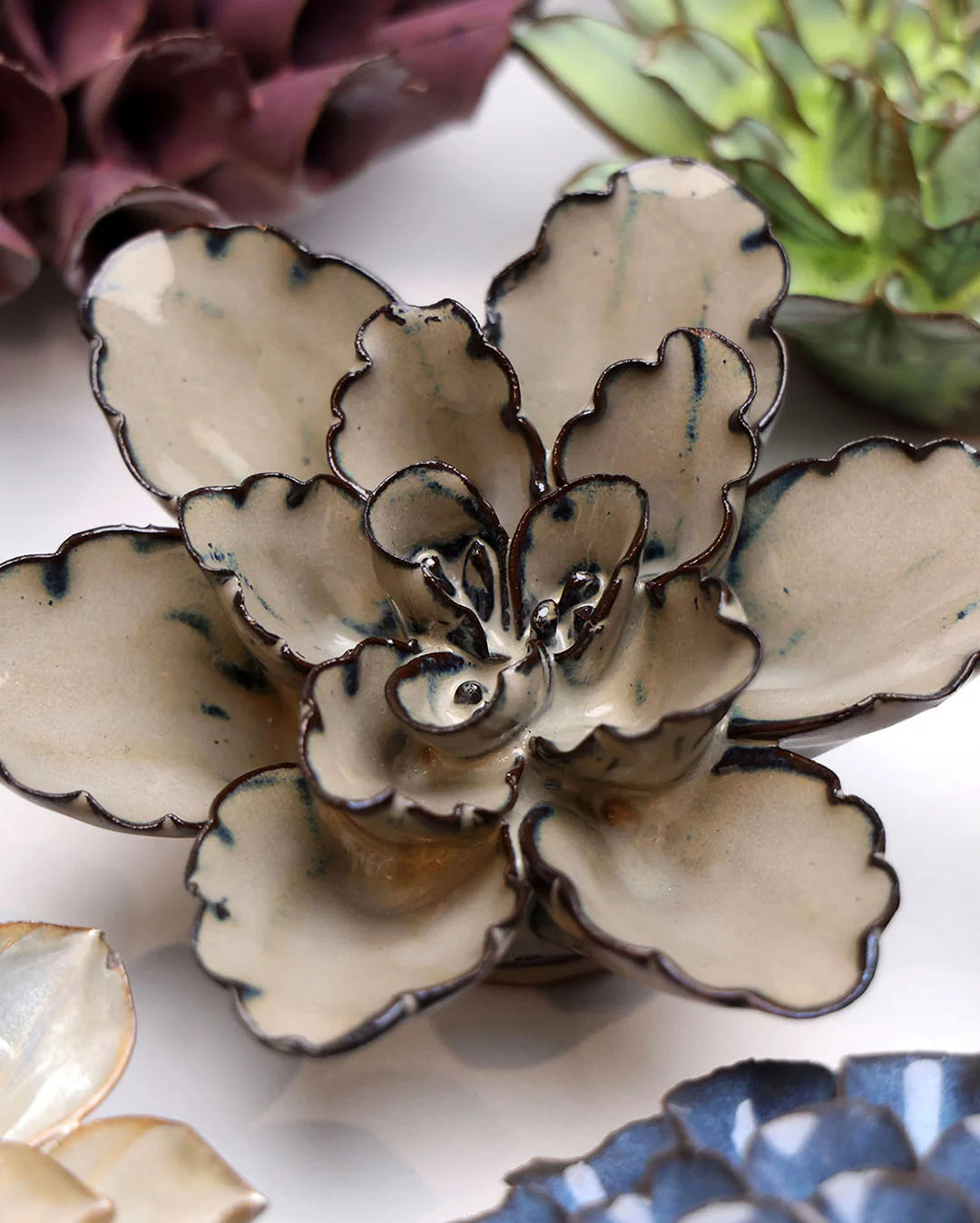 Latte Empress Lotus ceramic wall flower styled on a white table with other flowers — Chive Studio