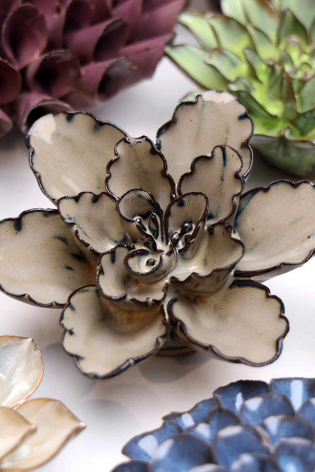 Latte Empress Lotus ceramic wall flower styled on a white table with other flowers — Chive Studio