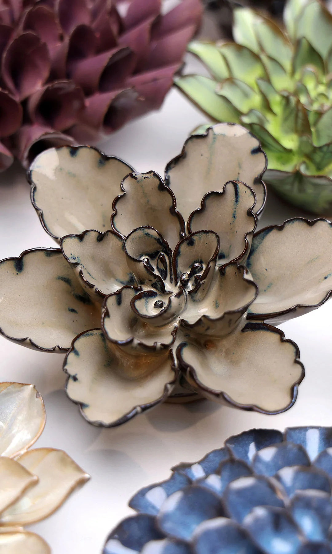 Latte Empress Lotus ceramic wall flower styled on a white table with other flowers — Chive Studio