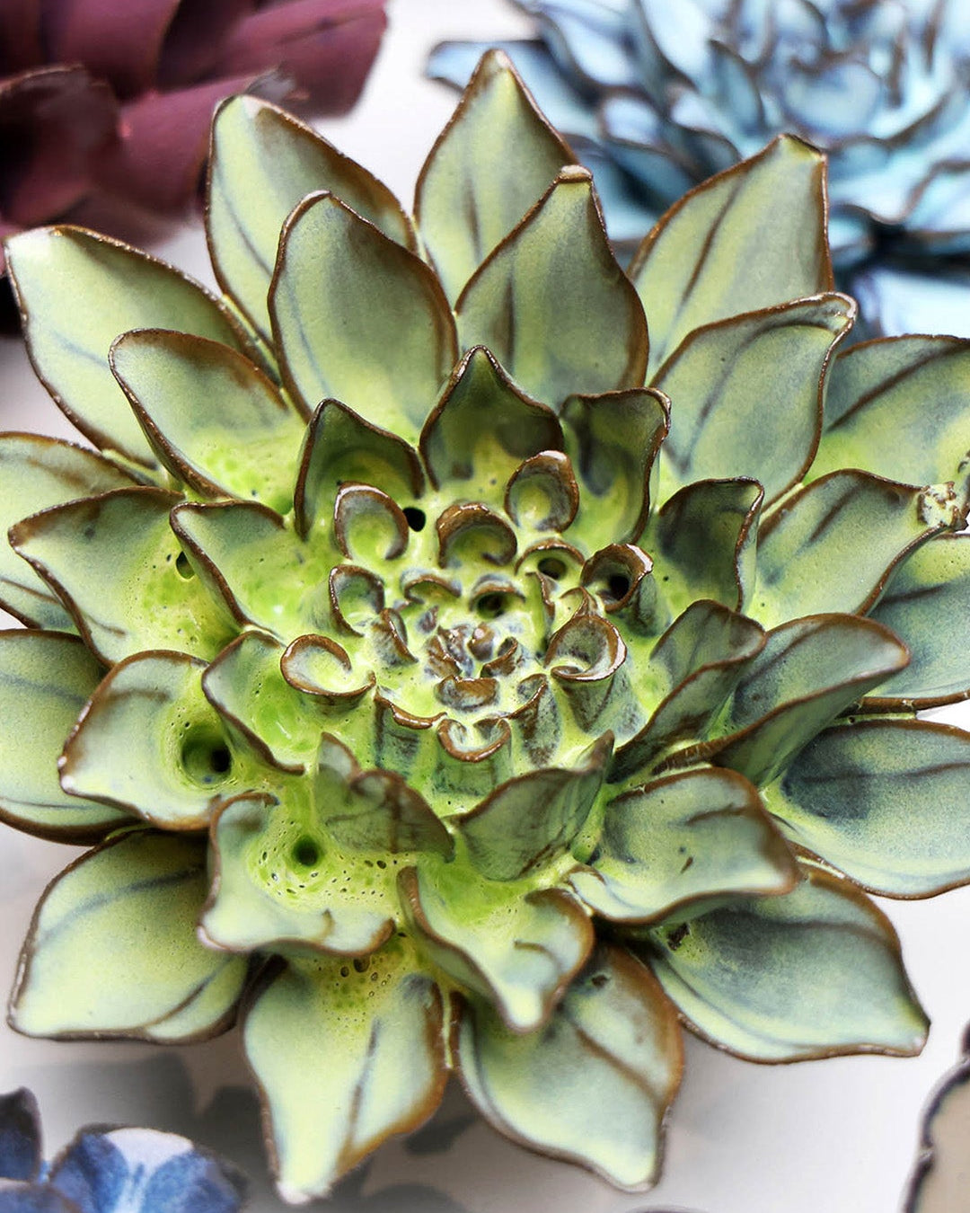 Green Aster ceramic wall flower styled on a white table with other flowers — Chive Studio