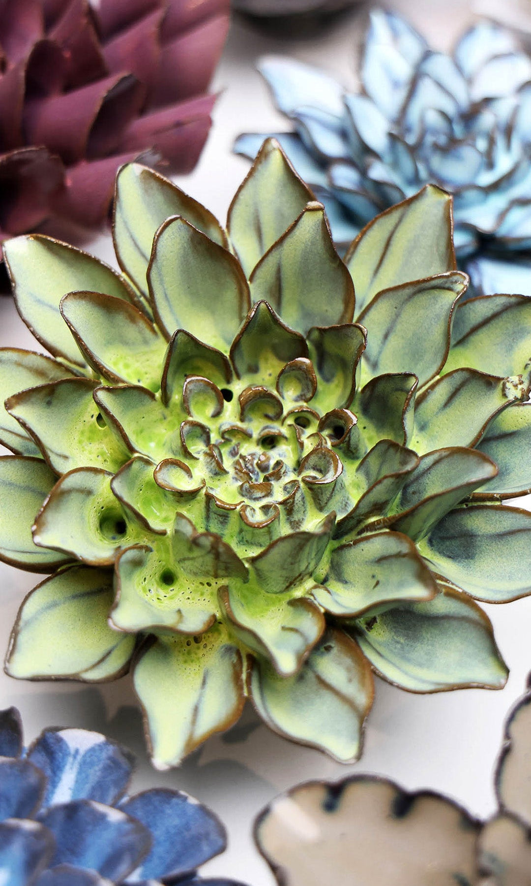 Green Aster ceramic wall flower styled on a white table with other flowers — Chive Studio