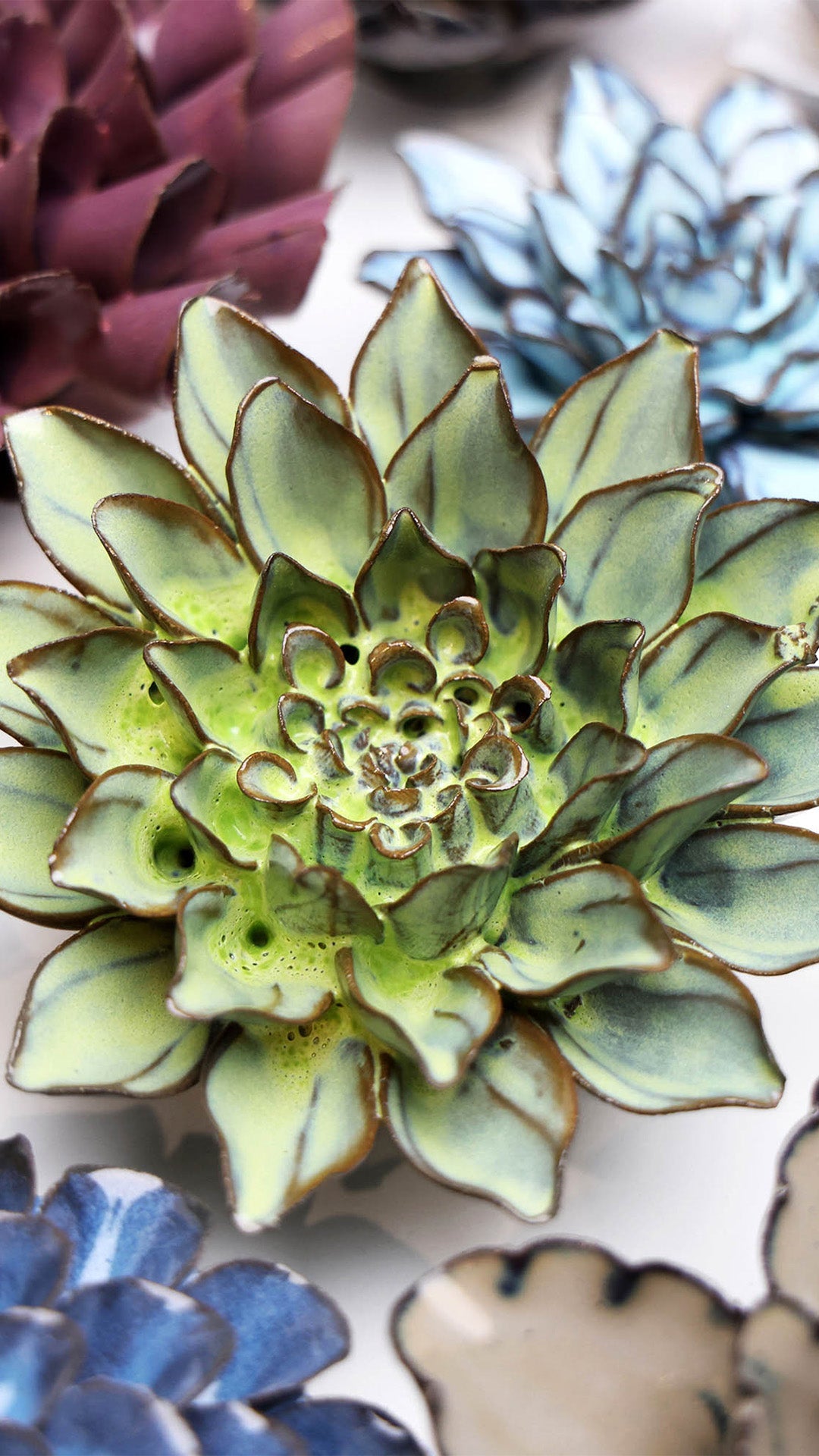 Green Aster ceramic wall flower styled on a white table with other flowers — Chive Studio