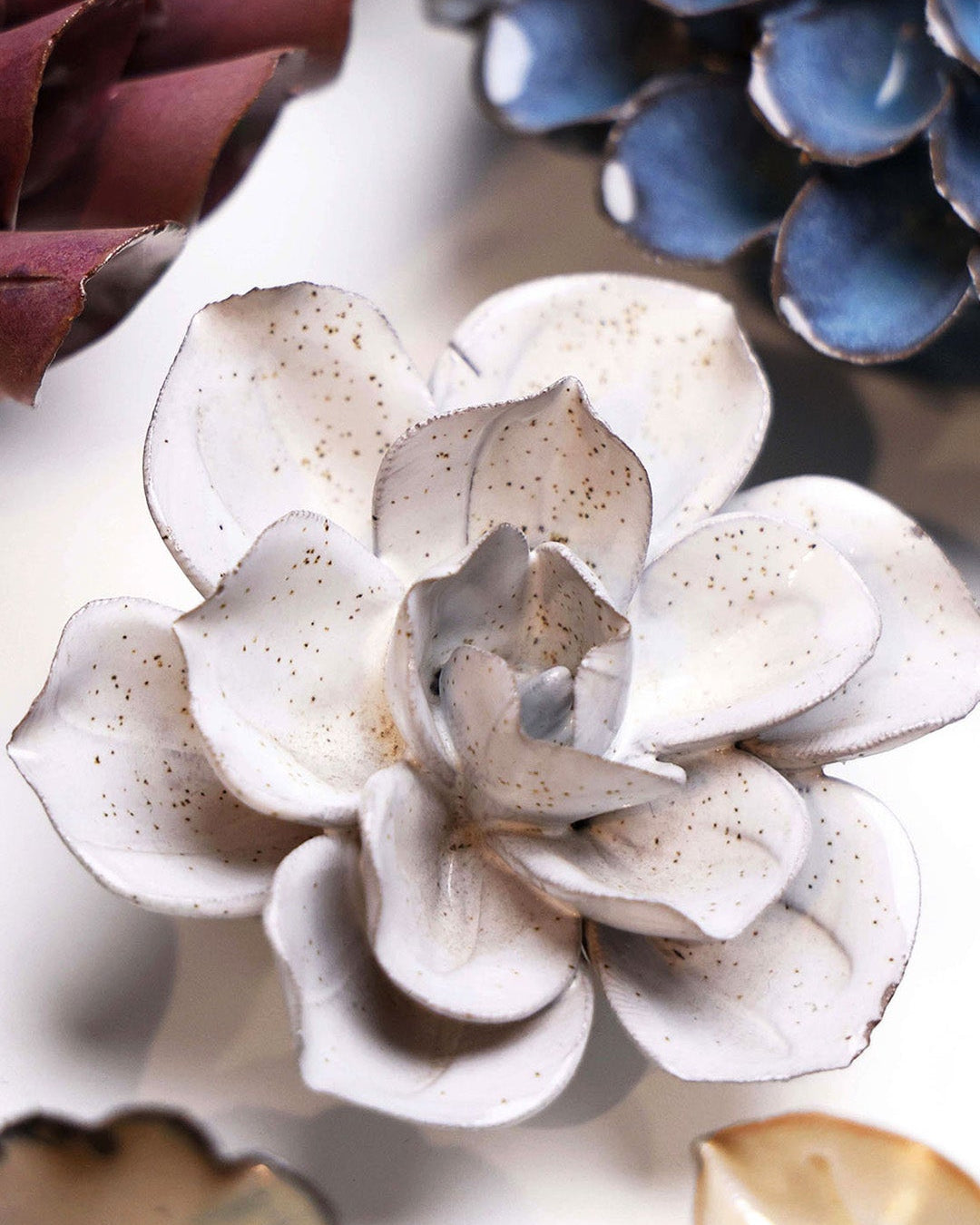 Cement Aqualla Gardenia ceramic wall flower styled on a white table with other flowers — Chive Studio