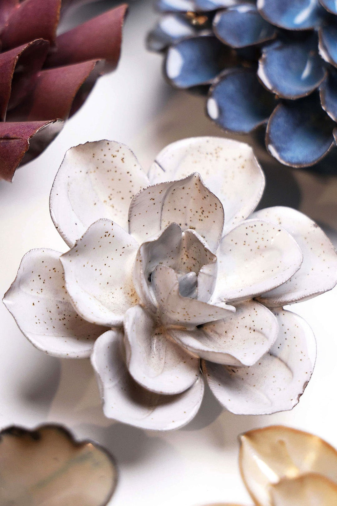 Cement Aqualla Gardenia ceramic wall flower styled on a white table with other flowers — Chive Studio