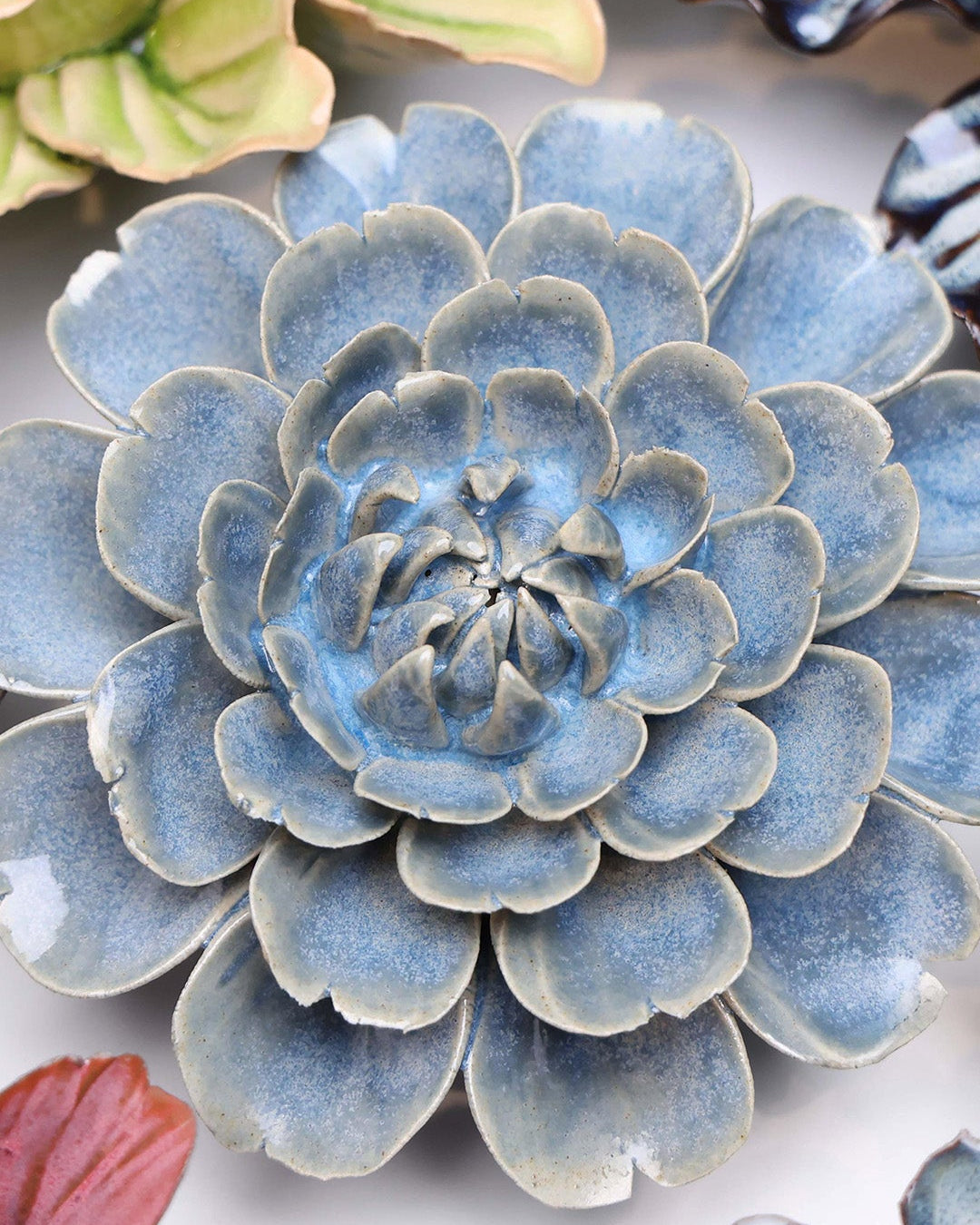 Blue Marigold ceramic wall flower styled on a white table with other flowers — Chive Studio