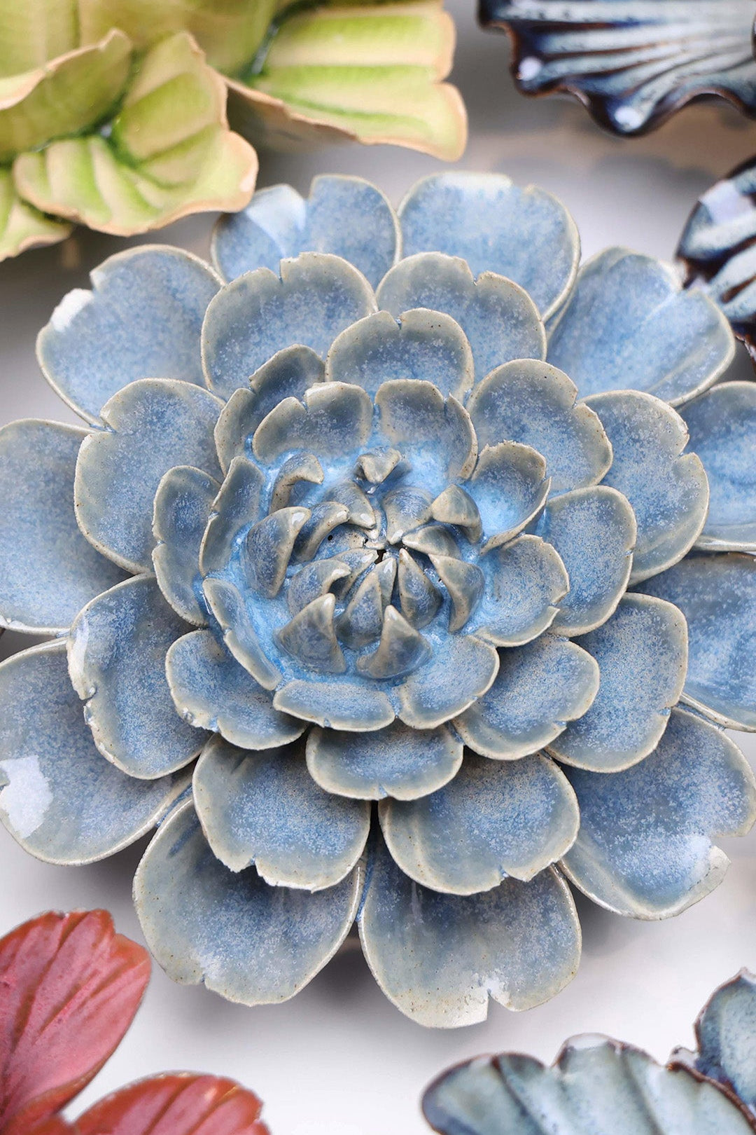 Blue Marigold ceramic wall flower styled on a white table with other flowers — Chive Studio