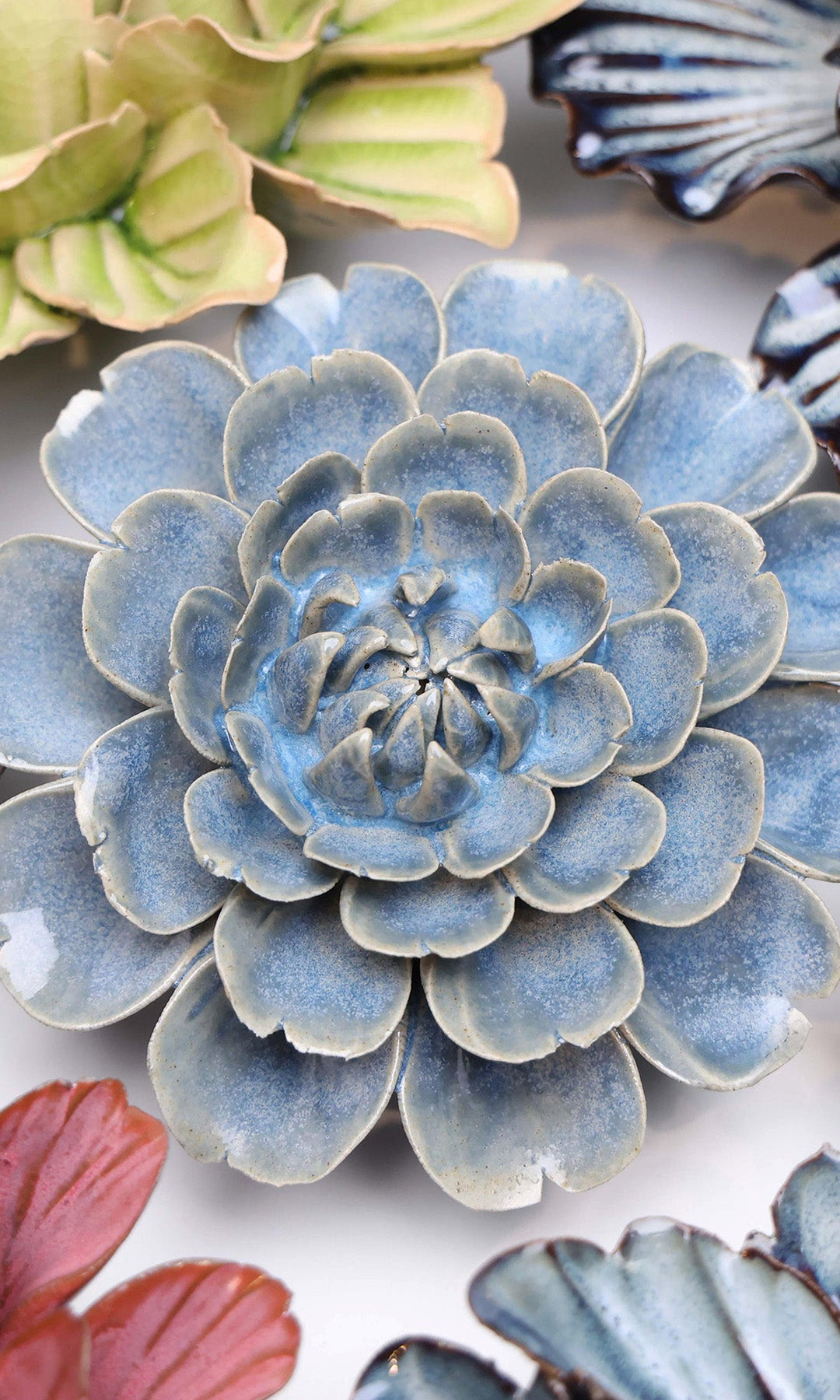 Blue Marigold ceramic wall flower styled on a white table with other flowers — Chive Studio
