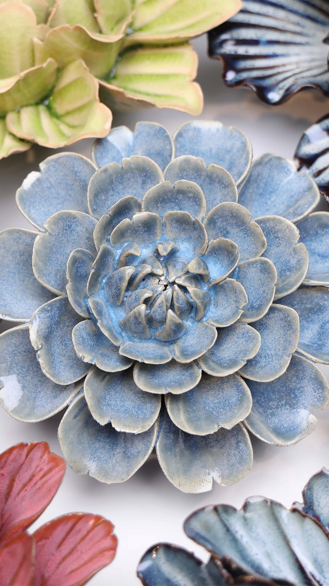 Blue Marigold ceramic wall flower styled on a white table with other flowers — Chive Studio