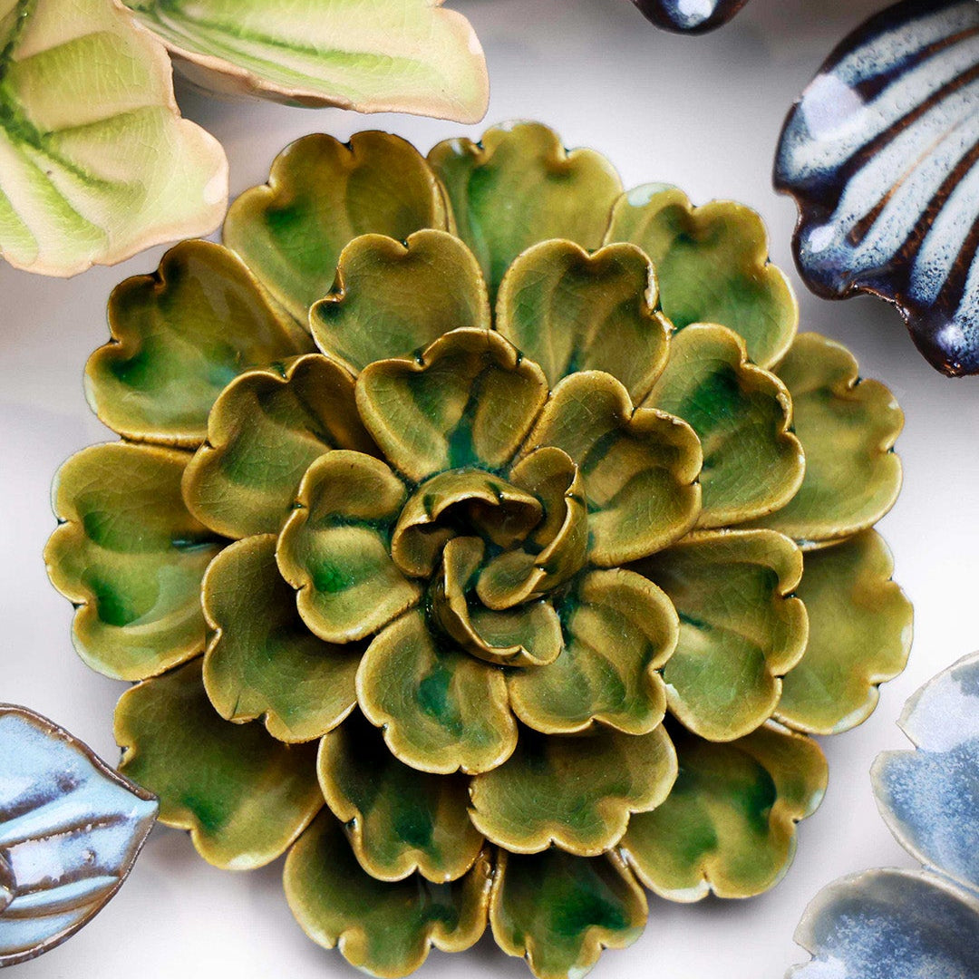 Avocado Green Petunia ceramic wall flower styled on a white table with other flowers — Chive Studio