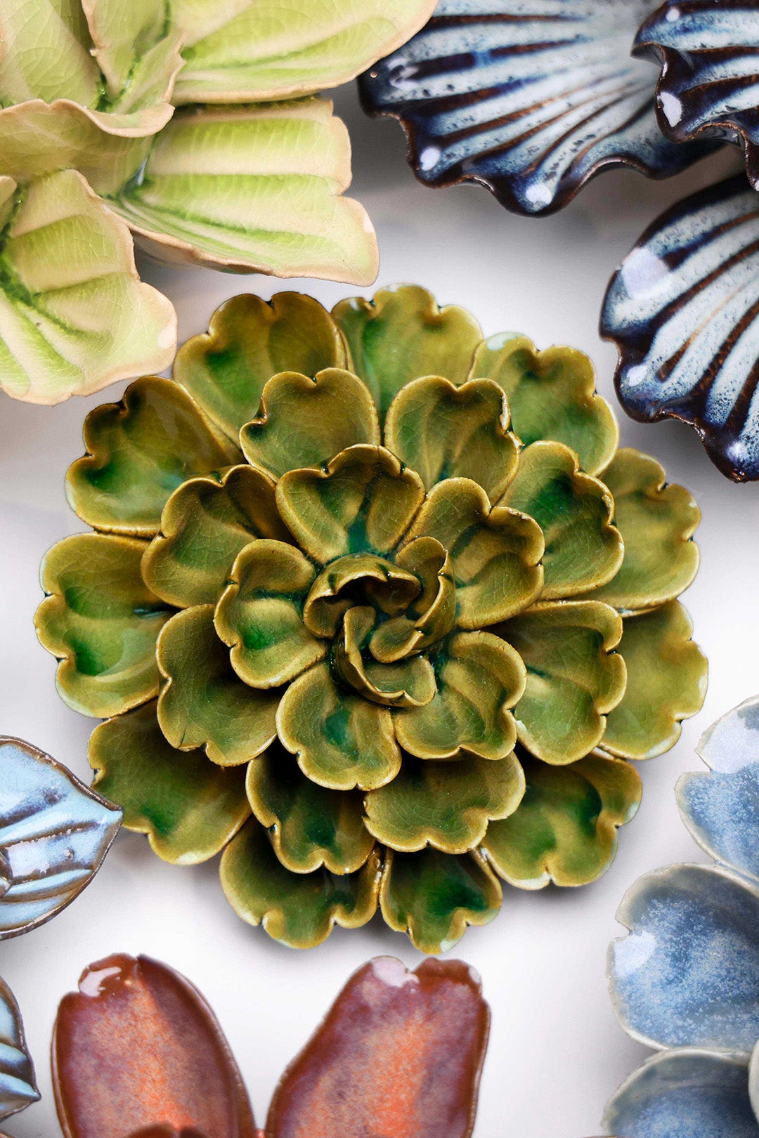 Avocado Green Petunia ceramic wall flower styled on a white table with other flowers — Chive Studio