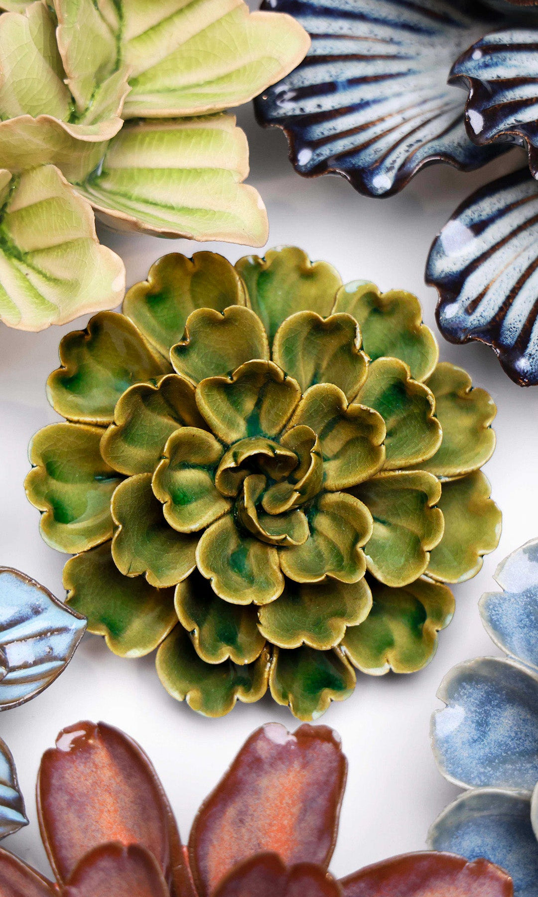 Avocado Green Petunia ceramic wall flower styled on a white table with other flowers — Chive Studio
