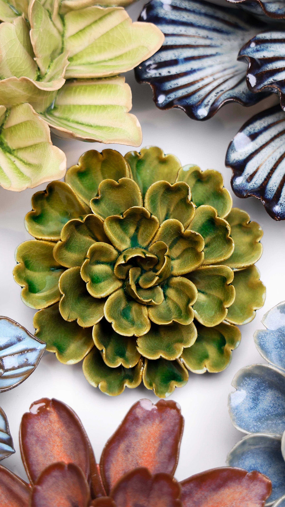 Avocado Green Petunia ceramic wall flower styled on a white table with other flowers — Chive Studio