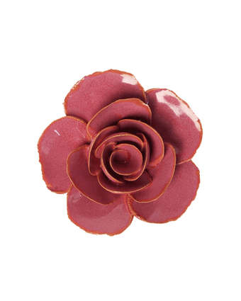 A glossy rose-shaped decorative object or accessory in a deep pinkish-red color with a subtle gold-toned edge, isolated on a solid black background.