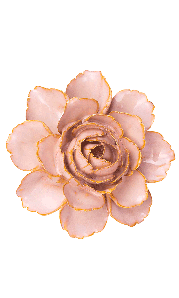 A single artificial flower bloom with pale blush pink petals and metallic gold edging, photographed from above on a plain white background.