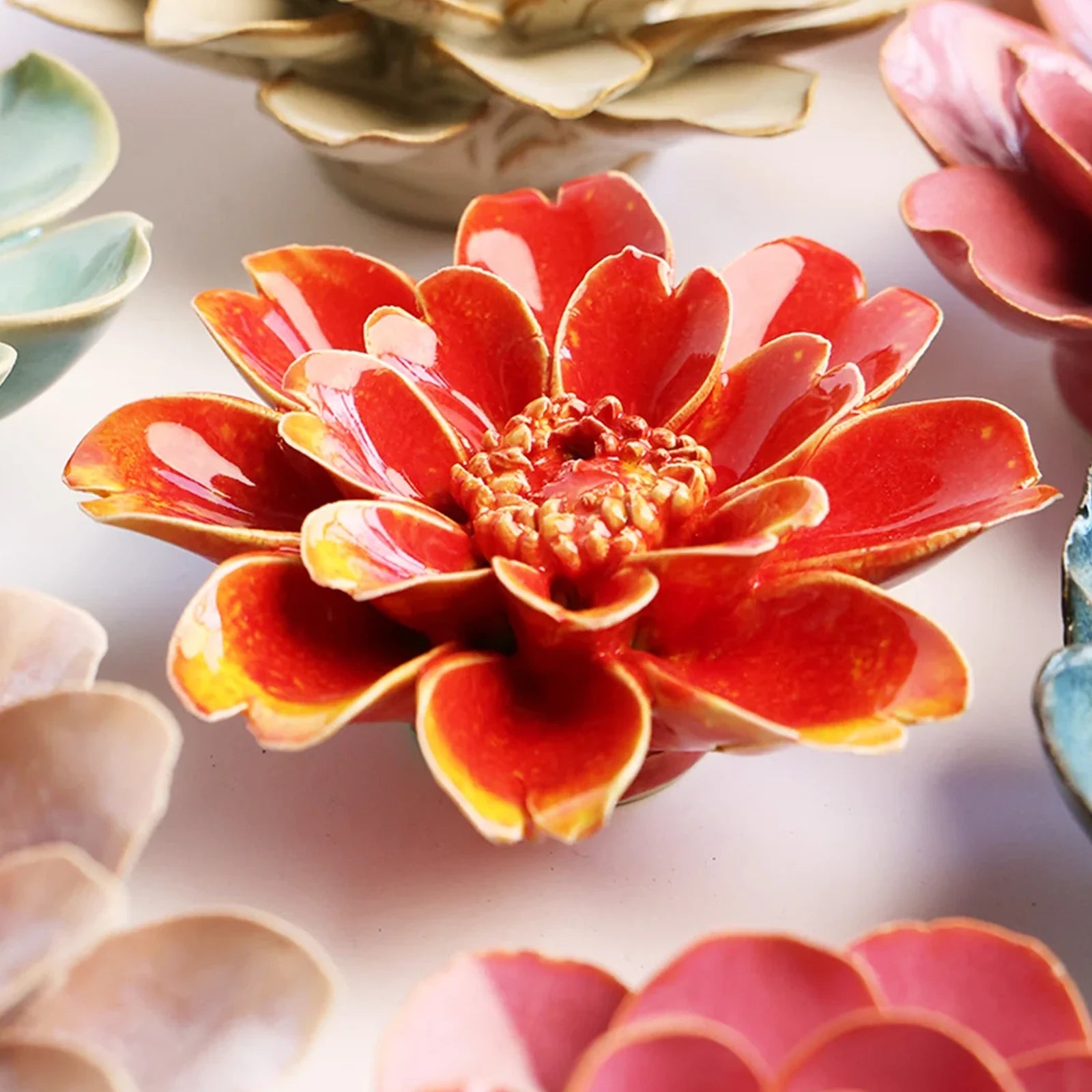 Close-up of the Chive April Birth Flower Daisy orange yellow ceramic flower among assorted Chive ceramic flowers.