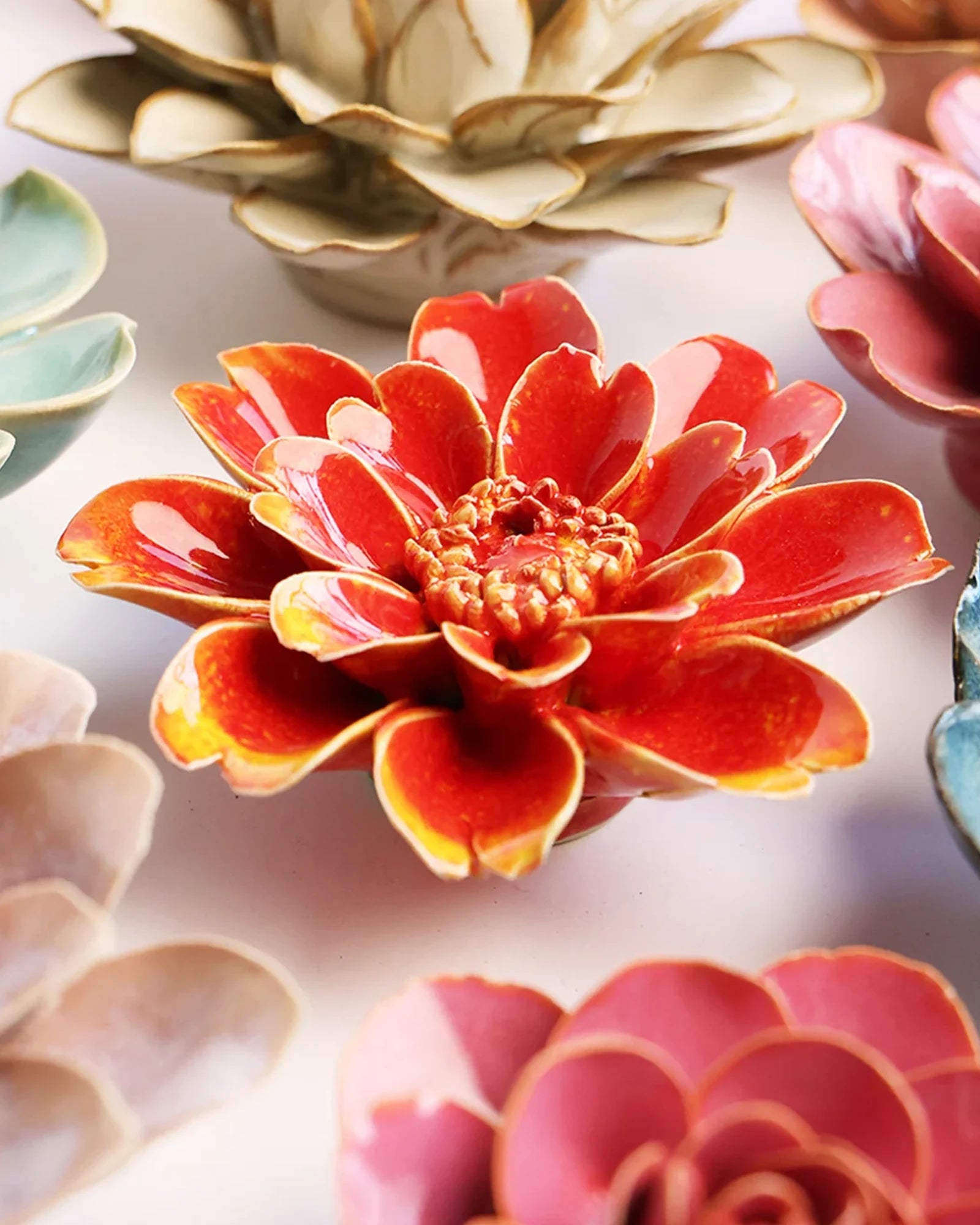 Close-up of the Chive April Birth Flower Daisy orange yellow ceramic flower among assorted Chive ceramic flowers.