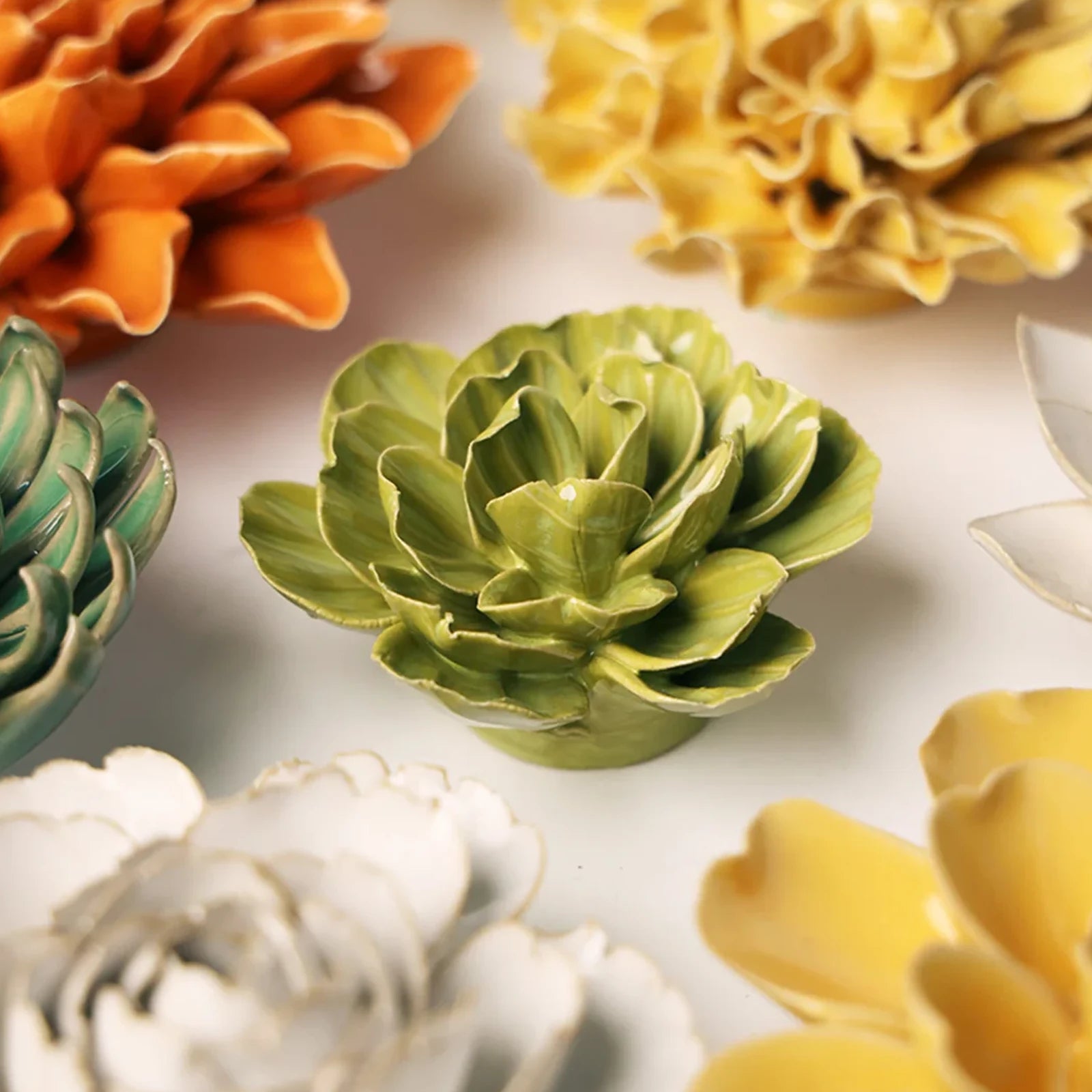 Close-up of the Chive February Birth Flower Primrose chartreuse ceramic flower among assorted Chive ceramic flowers.