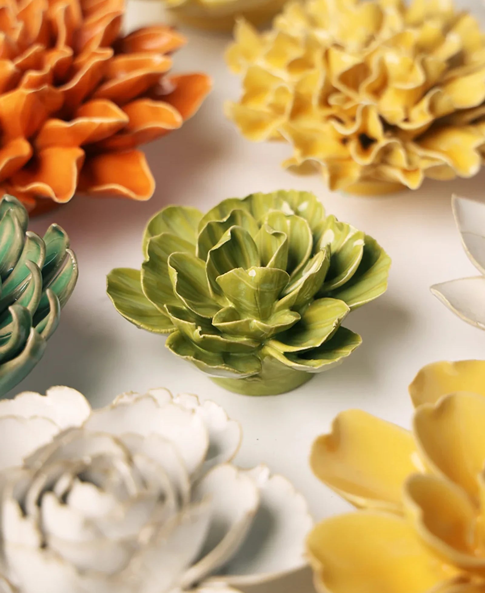 Close-up of the Chive February Birth Flower Primrose chartreuse ceramic flower among assorted Chive ceramic flowers.