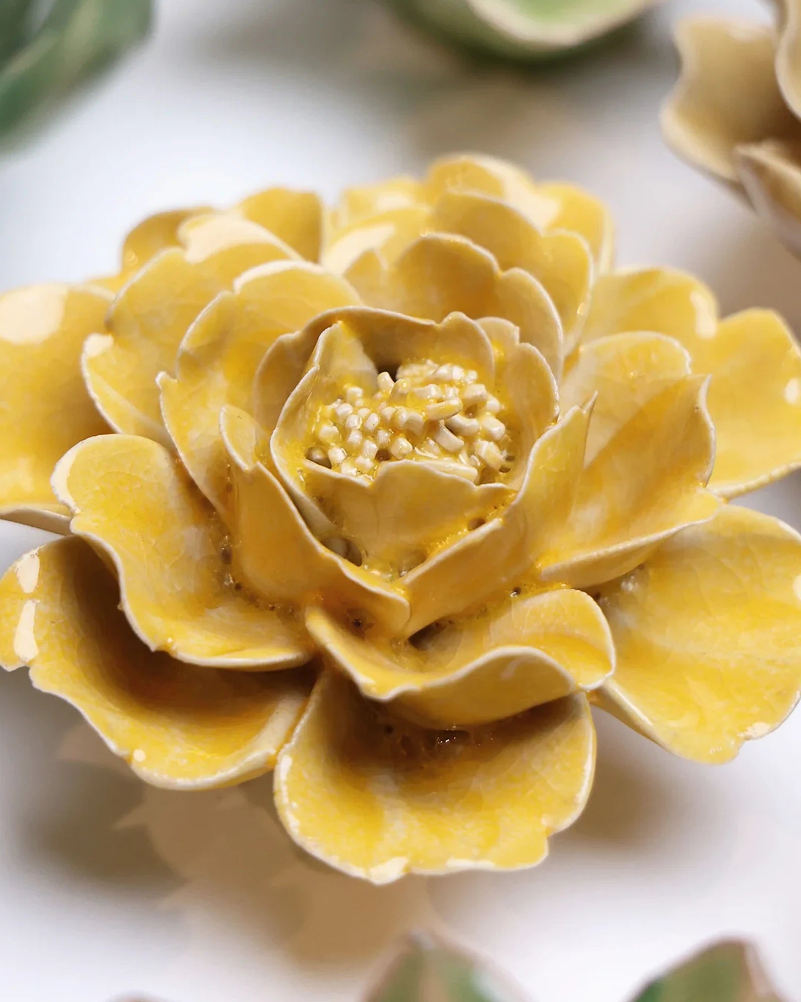 Close-up of the Chive June Birth Flower Rose burnt yellow ceramic flower among assorted Chive ceramic flowers.