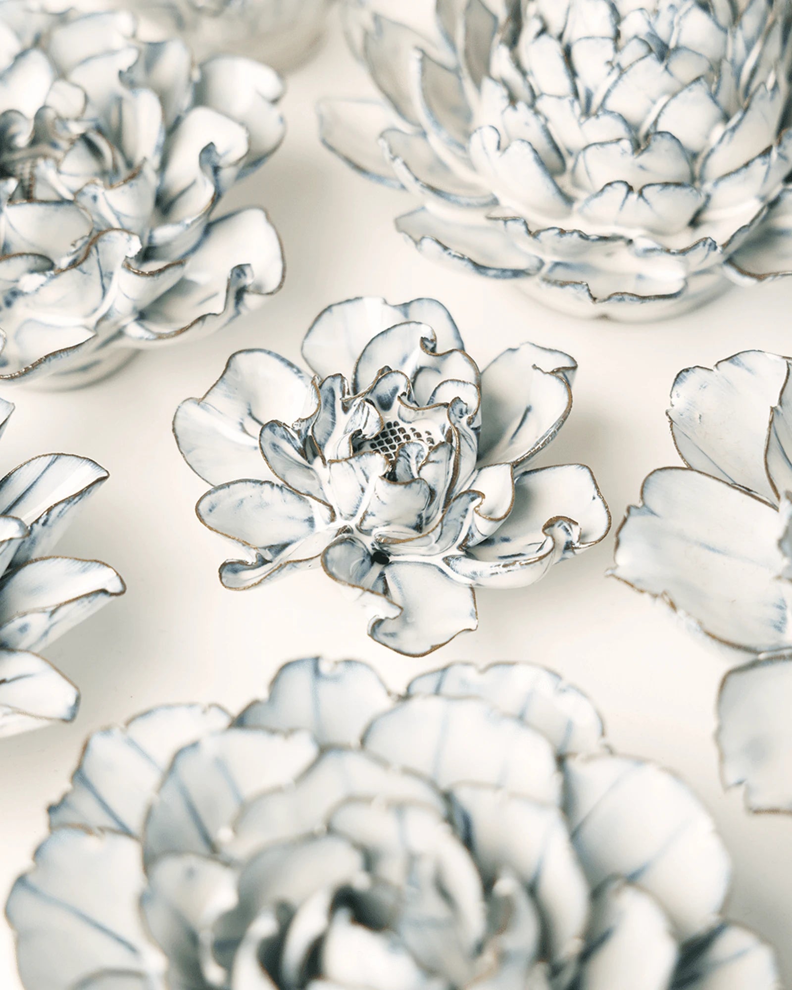 Close-up of the Chive May Birth Flower Hawthorn blue white ceramic flower among assorted Chive ceramic flowers.