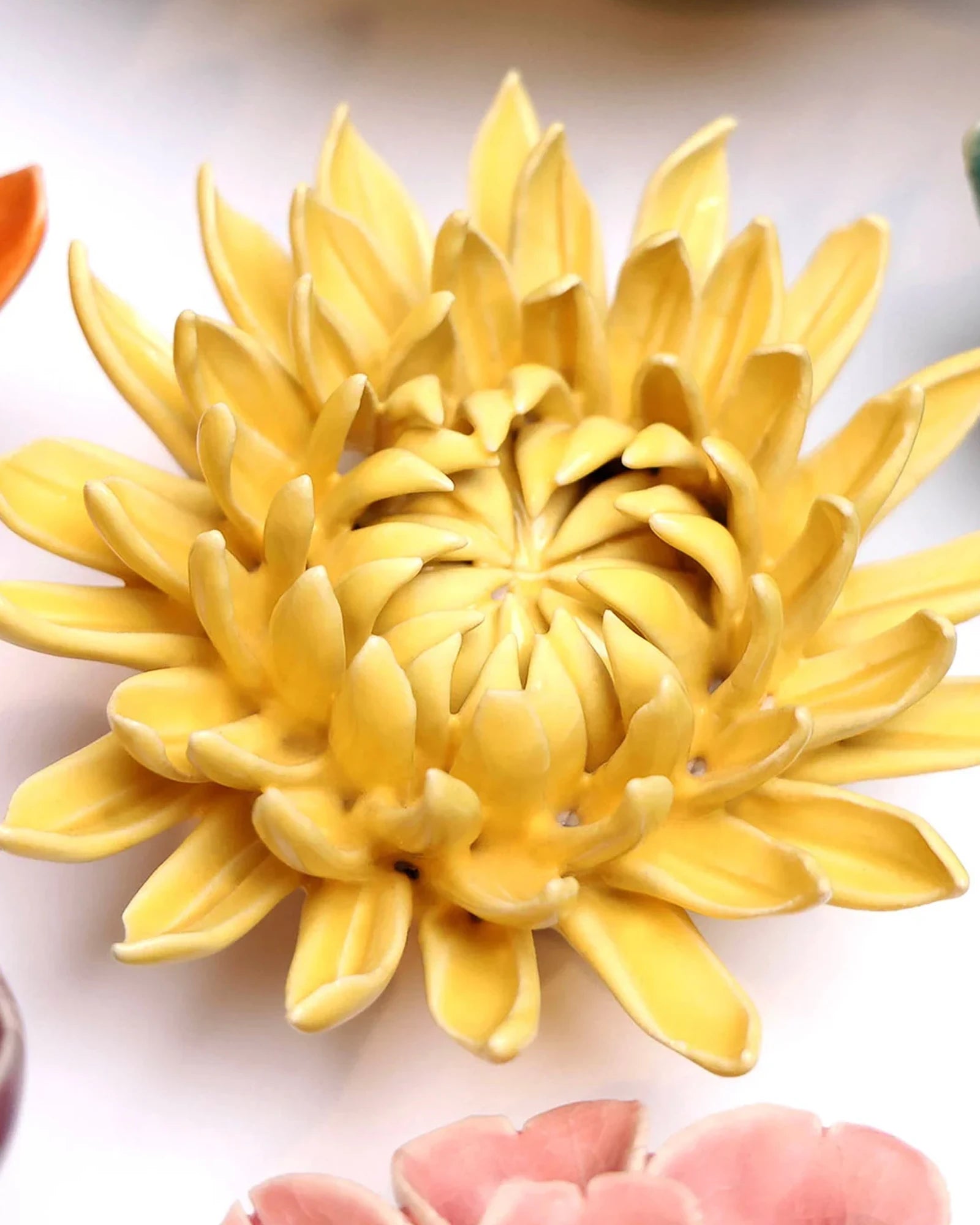Close-up of the Chive November Birth Flower Chrysanthemum yellow ceramic flower among assorted Chive ceramic flowers.