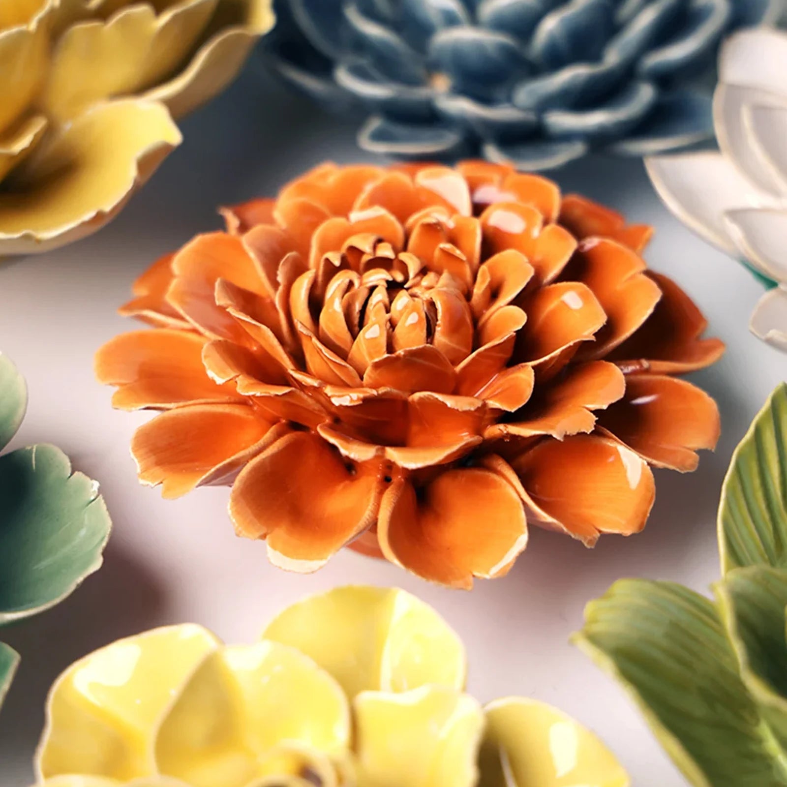 Close-up of the Chive October Birth Flower Marigold fiesta orange ceramic flower among assorted Chive ceramic flowers.