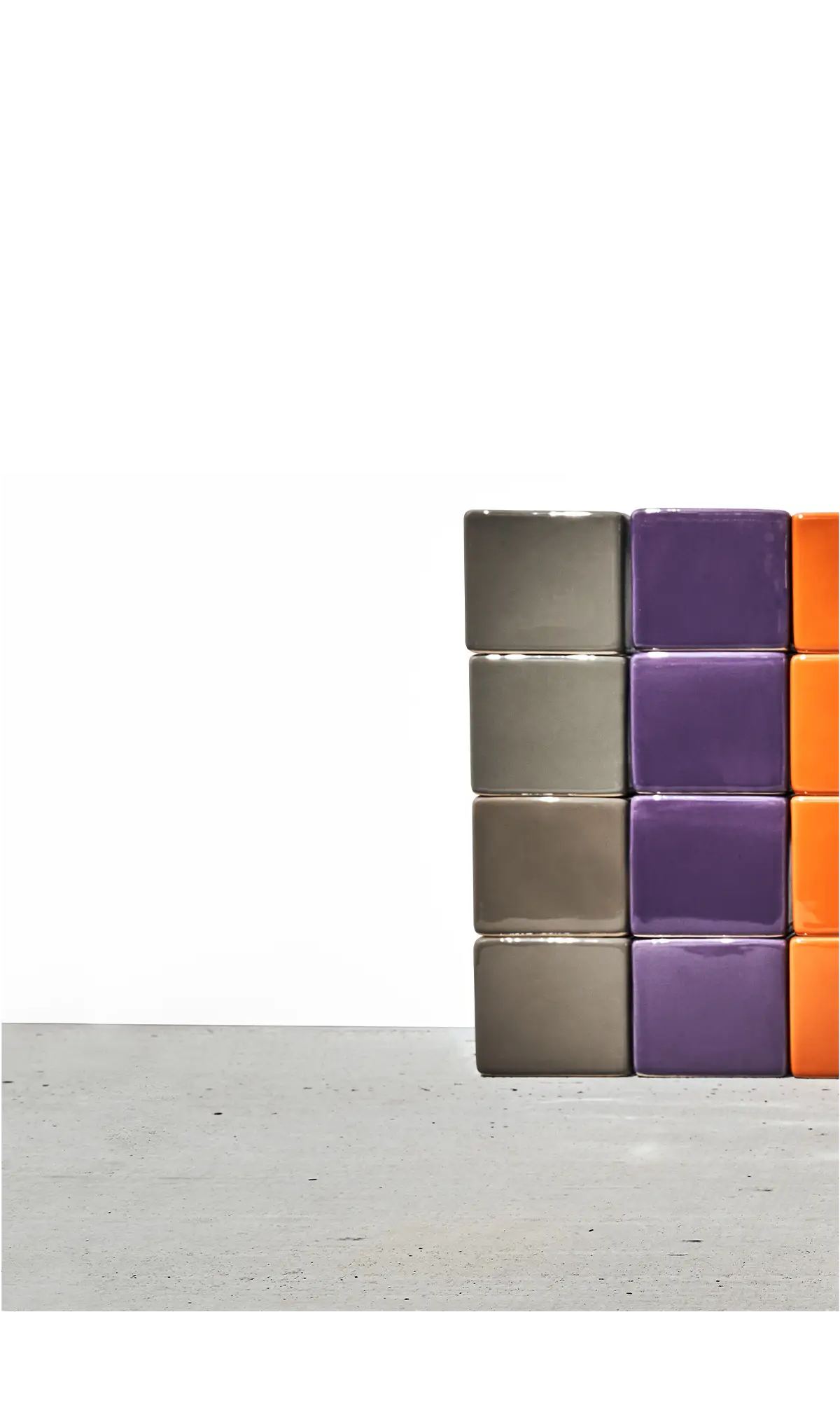Chive Cube Saucer ceramic planters stacked in columns of grey, purple, and orange on a concrete floor.