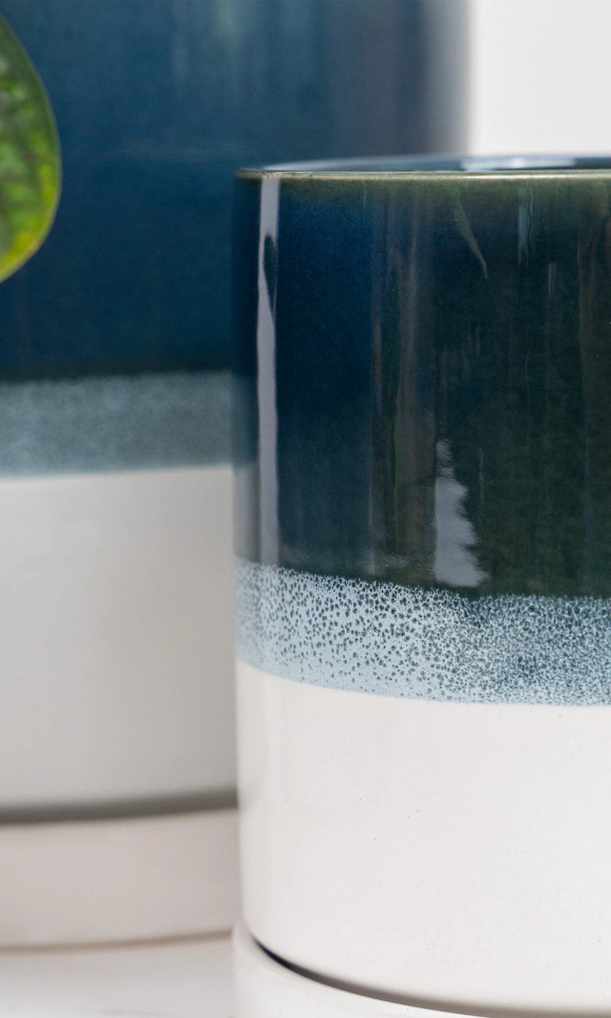 Close up of two Chive Minute green blue ceramic planter pots showing the color gradient and saucer detail.