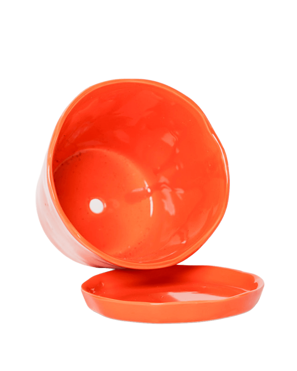 Close-up of the detachable saucer and drainage hole on a Chive Tika orange ceramic large pot.